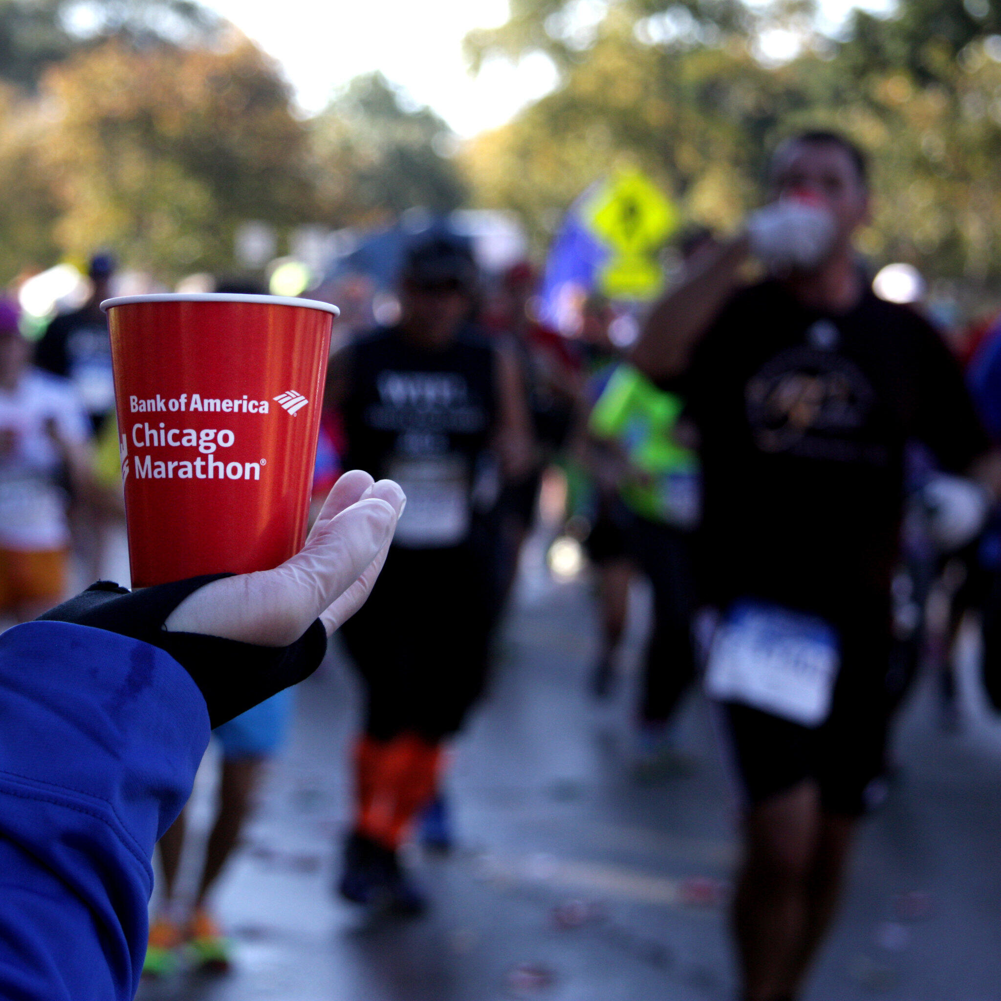 volunteer handing out water cups to runners passing by