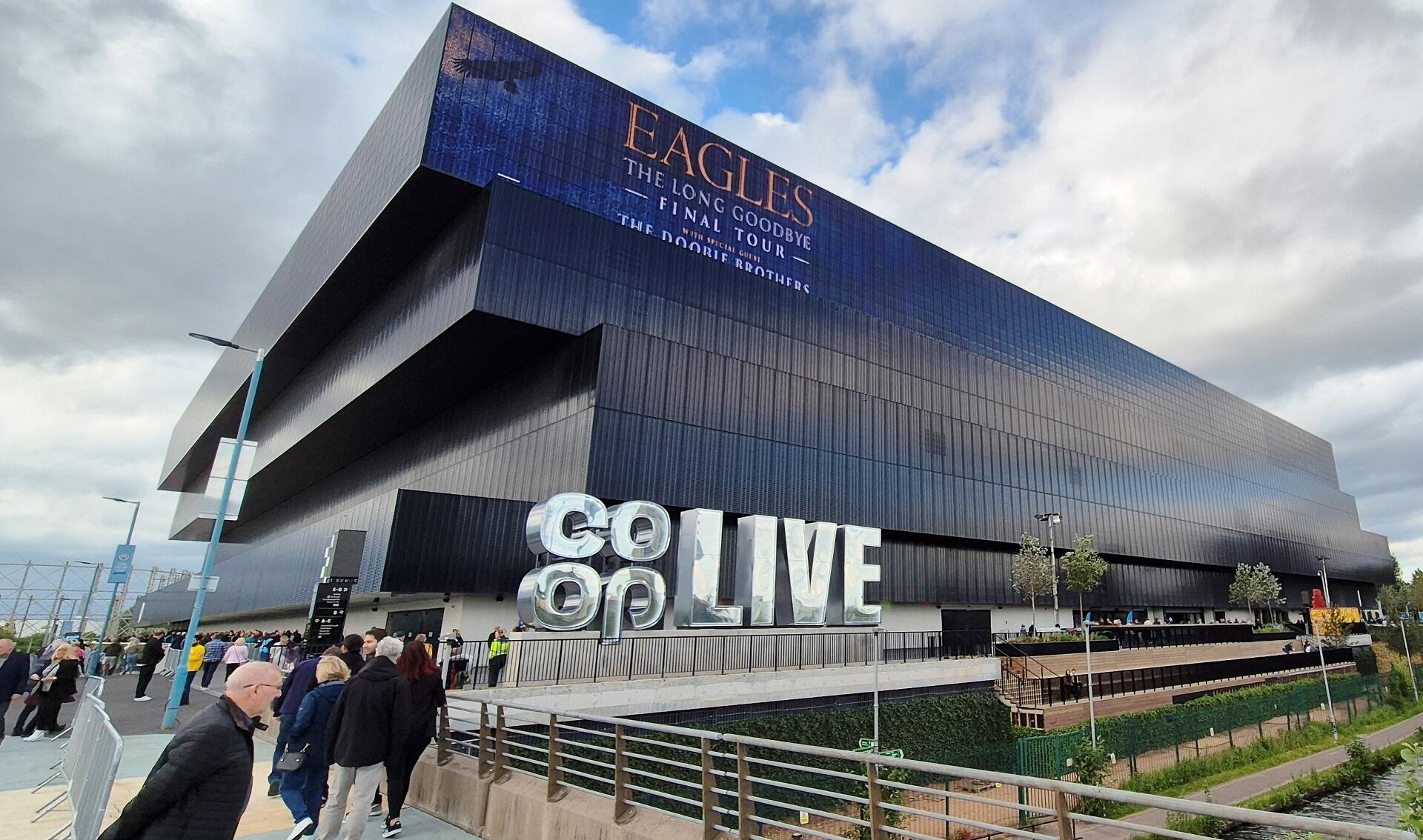 A large, stylish building with a silver sign in front of it on a sunny day.