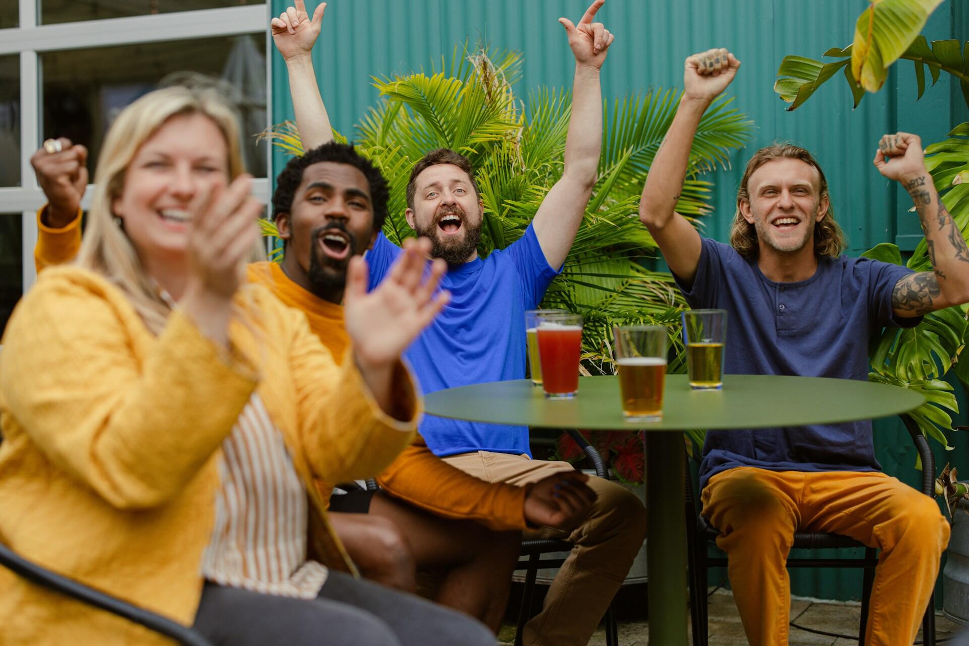 Four people sitting around a table cheering and clapping.