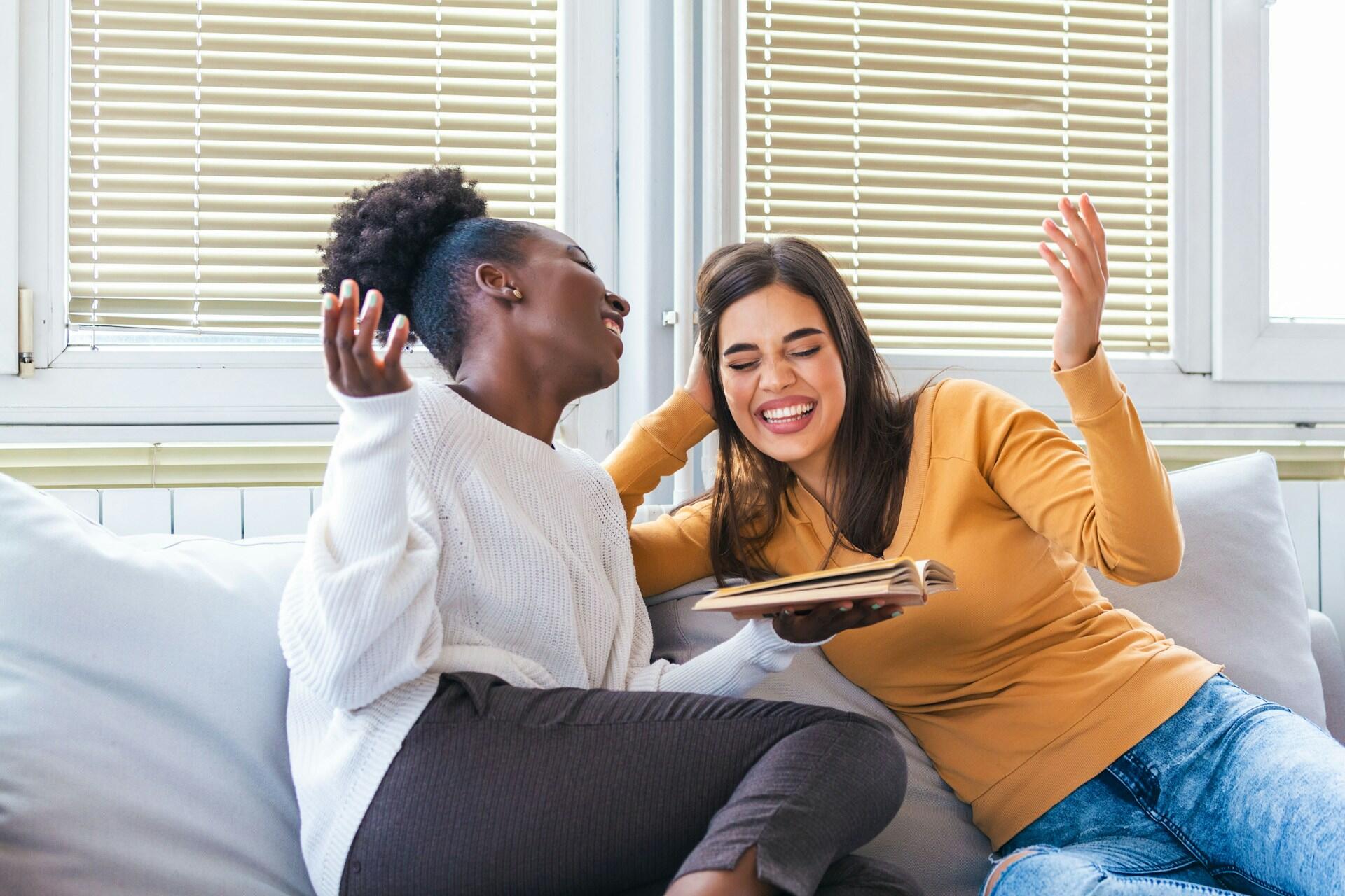 Two women engaged in a lively conversation while seated on a couch.