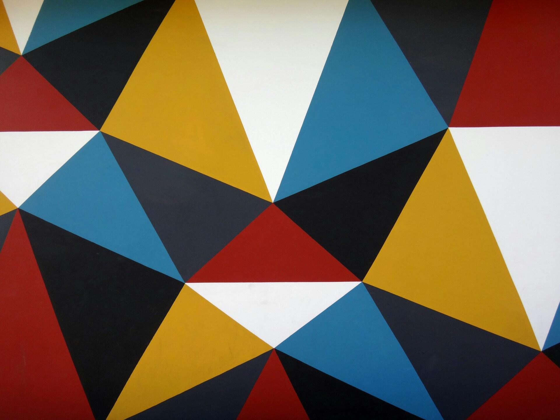 Wall displaying a colourful geometric pattern made from triangular shapes in red, blue, yellow, black, and white.