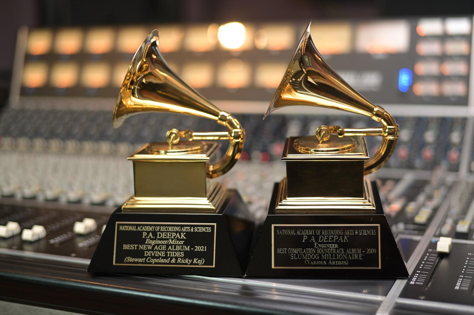 Two golden grammy statues in front of a bank of lights.