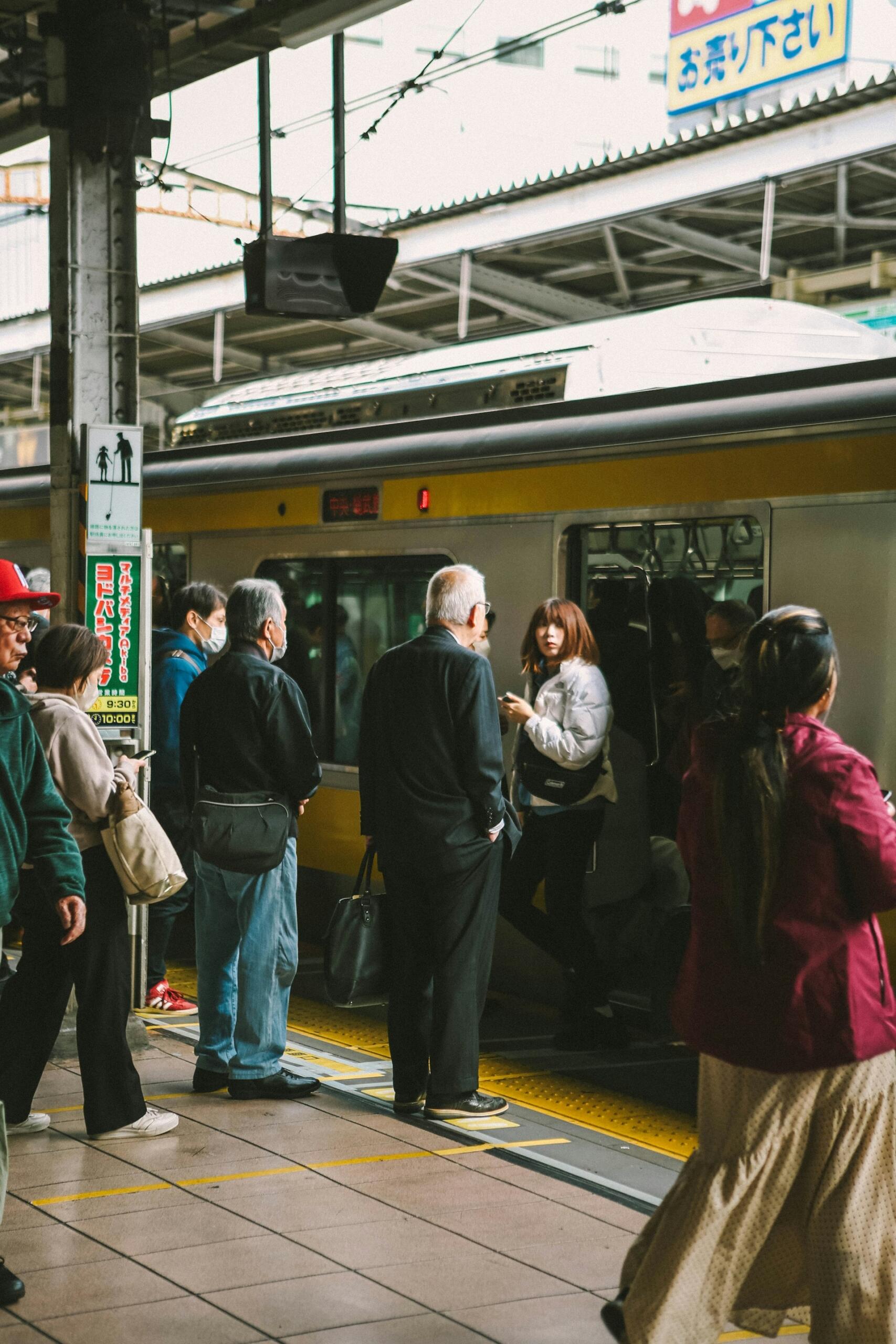 People on a train platform with some boarding the train. 