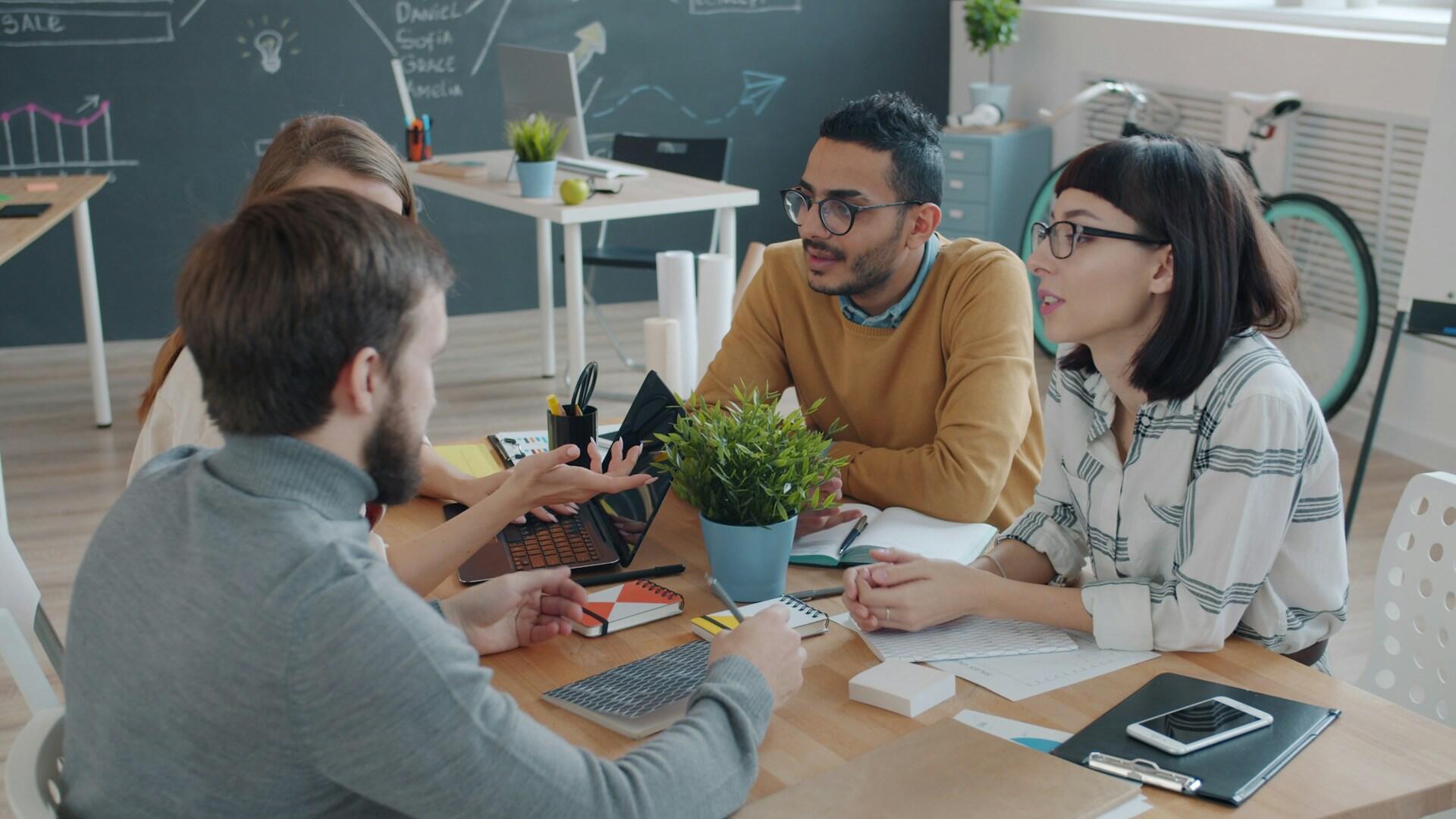 Four people sitting around a table, speaking.