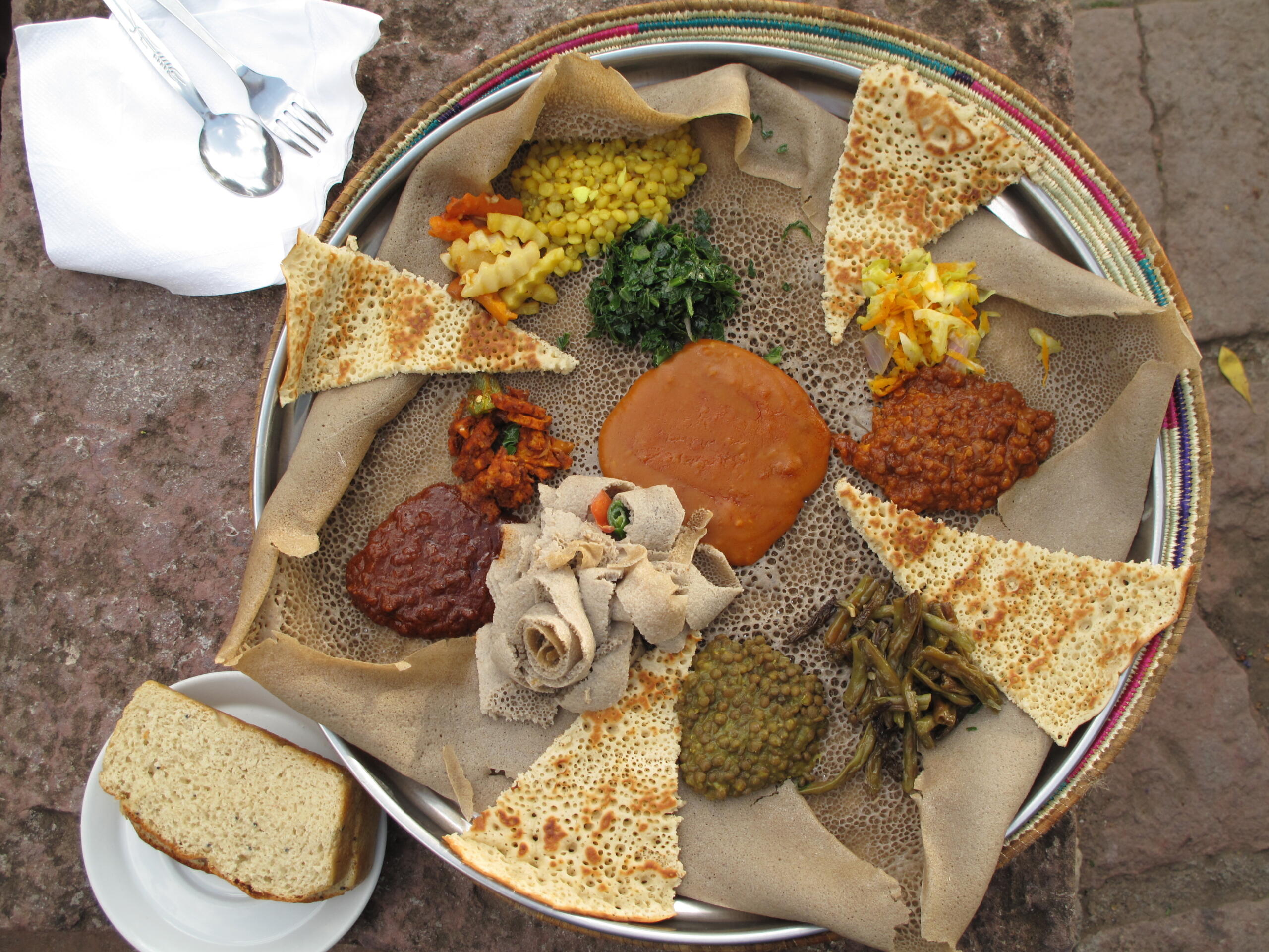 Ethiopian meal consisting of a large flatbread with several different vegetable preparations scooped on top. 
