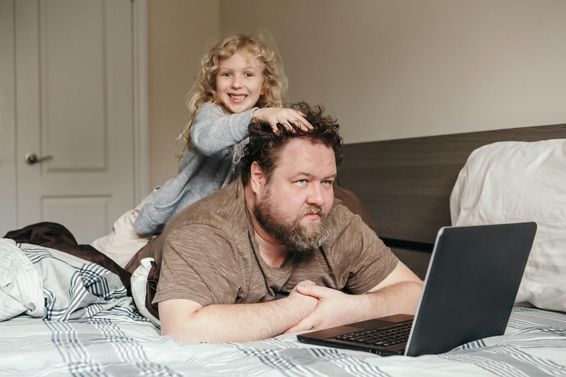 child interrupting her father while working on a laptop