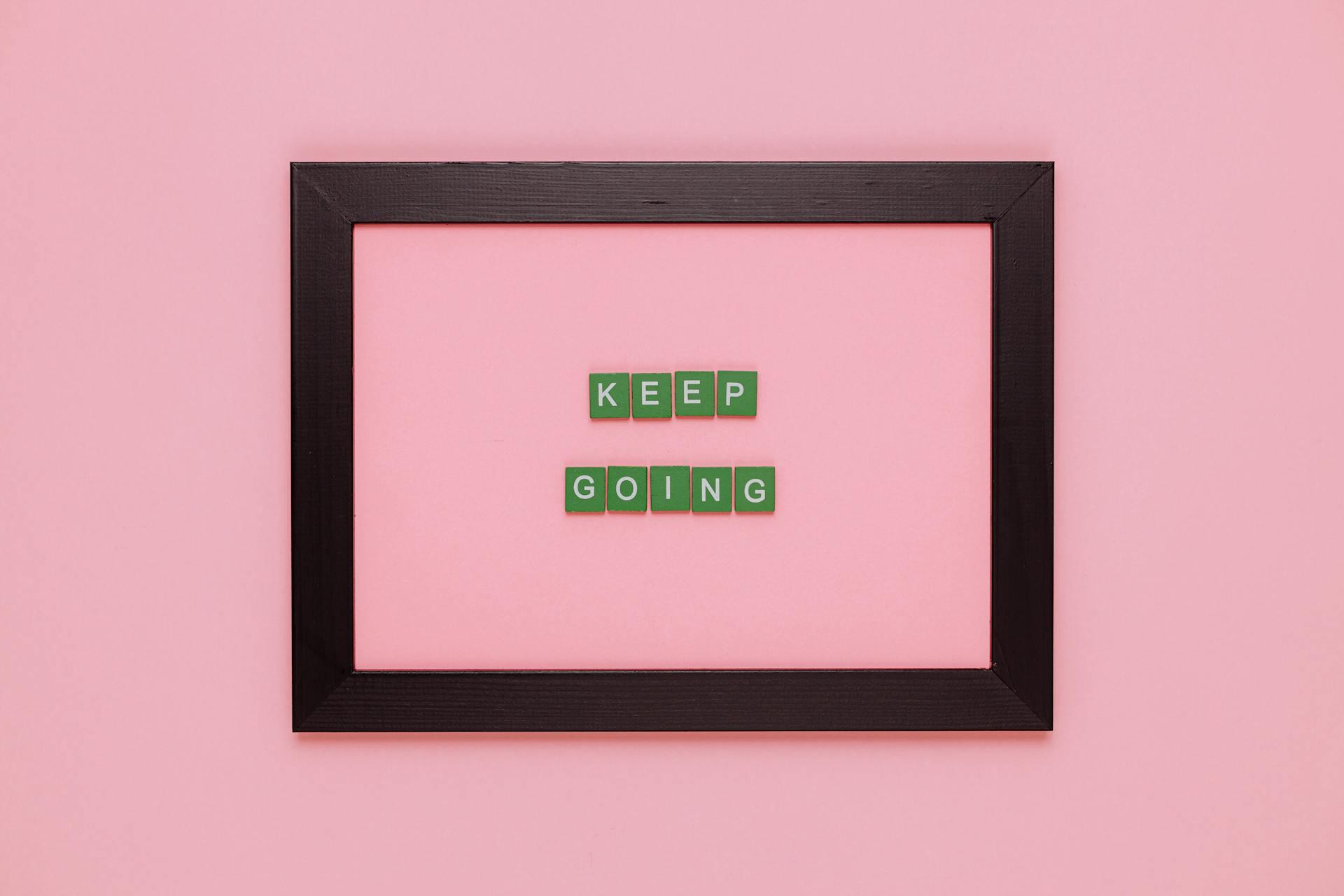 black frame with the words keep going inside, pink background