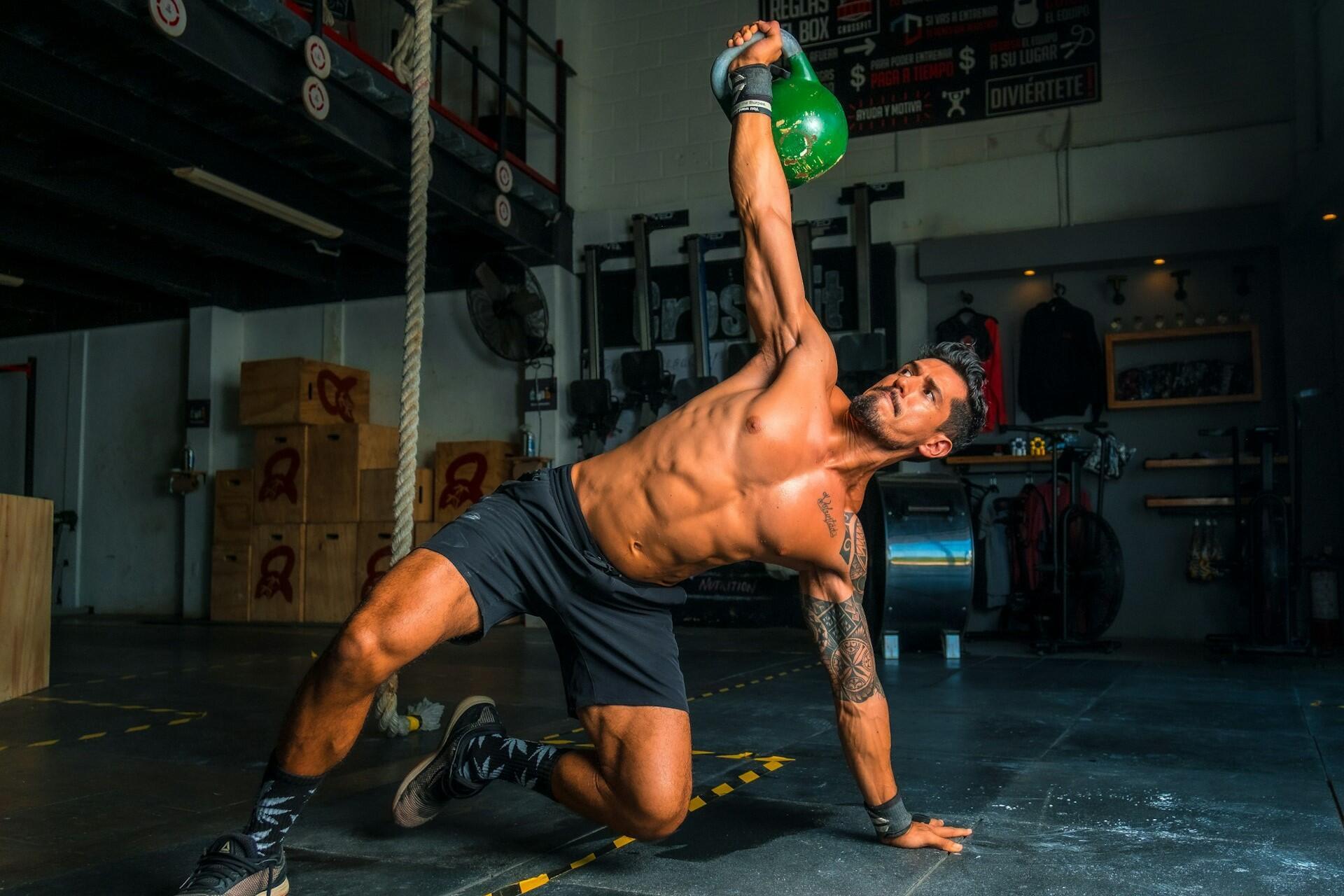 Man performing a kettlebell side plank exercise in a gym