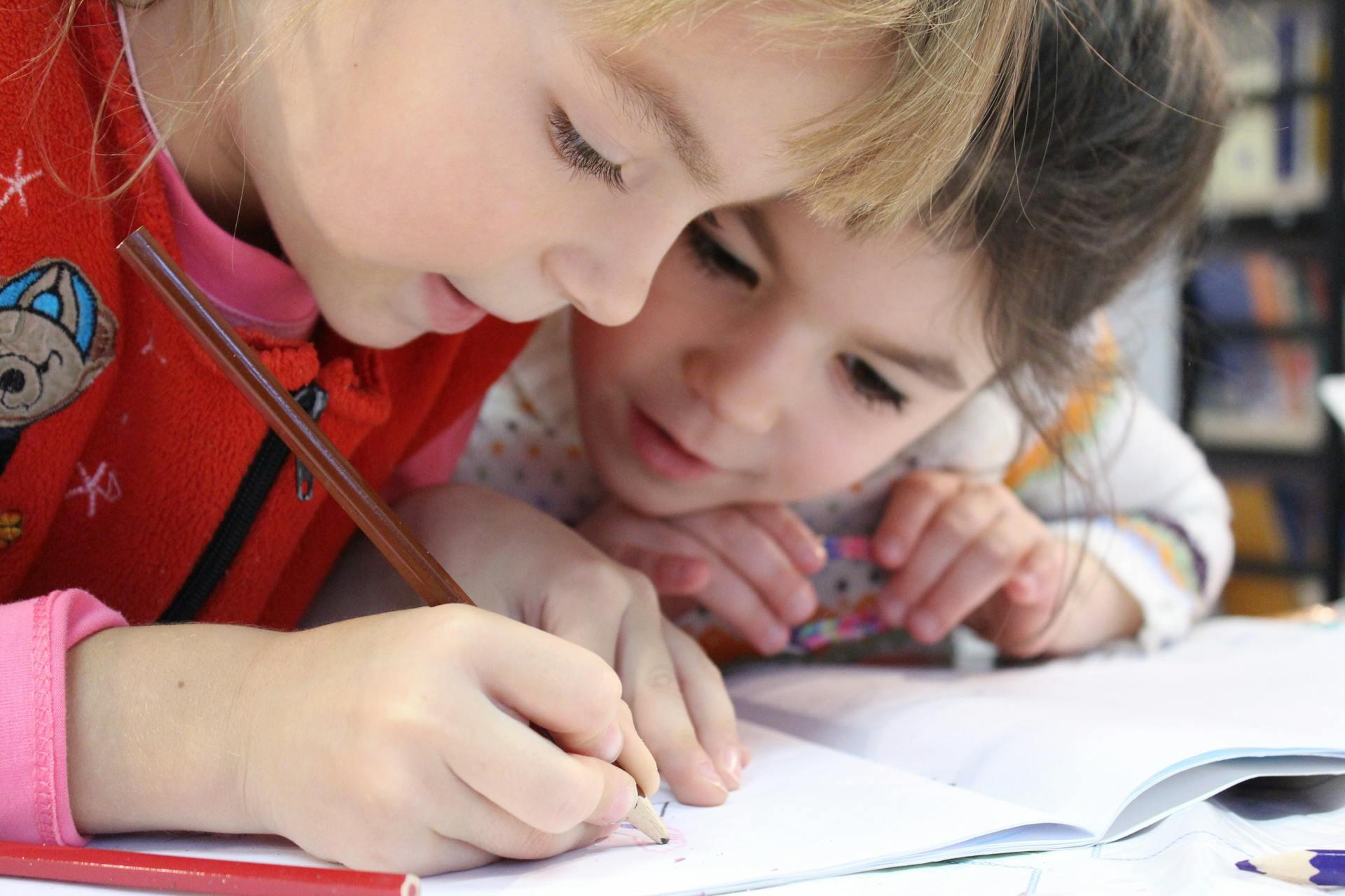 Two kids leaning over a school book