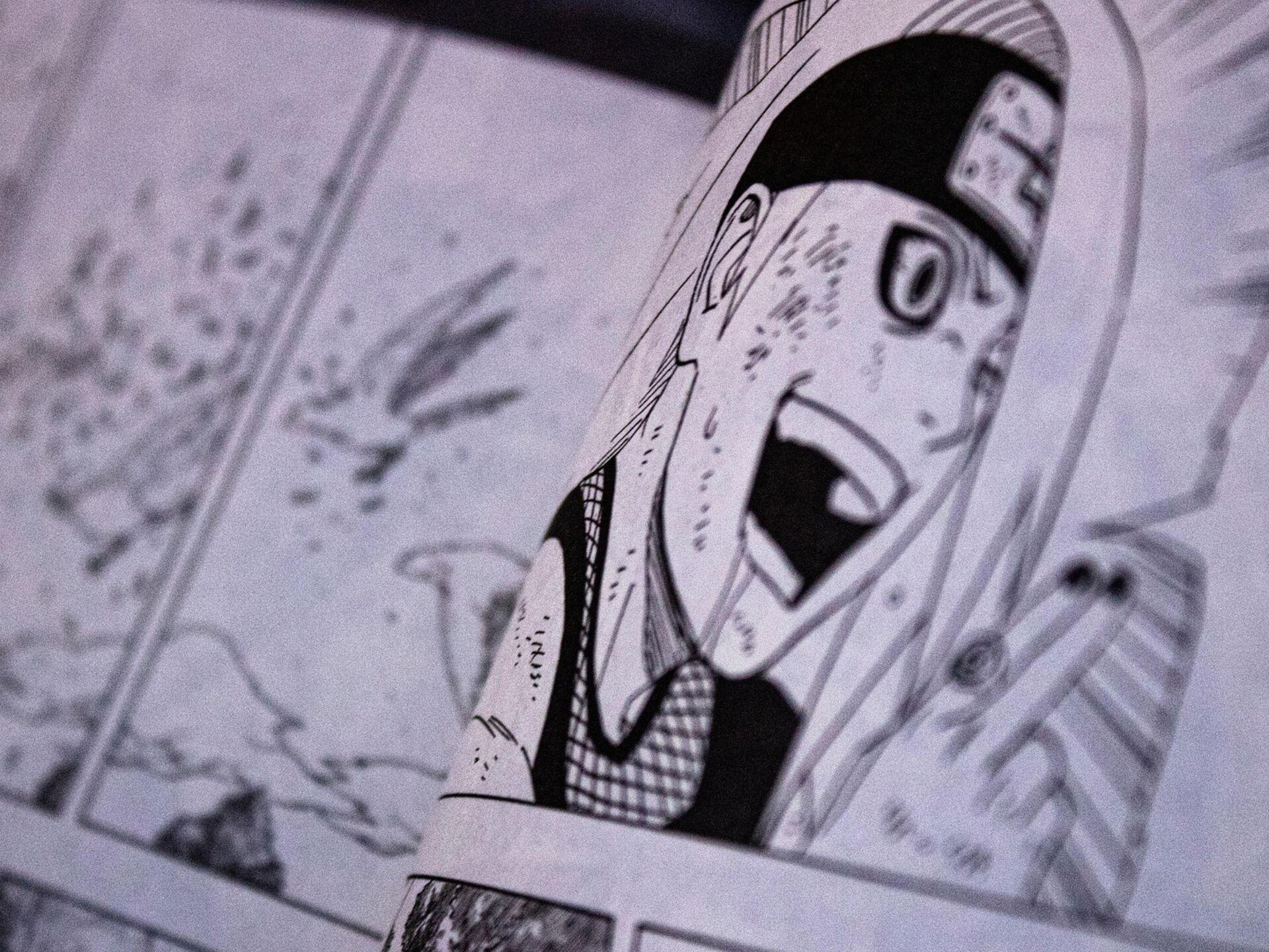 Close-up of an open manga showing a surprised character with a headband and open mouth in black and white panels.