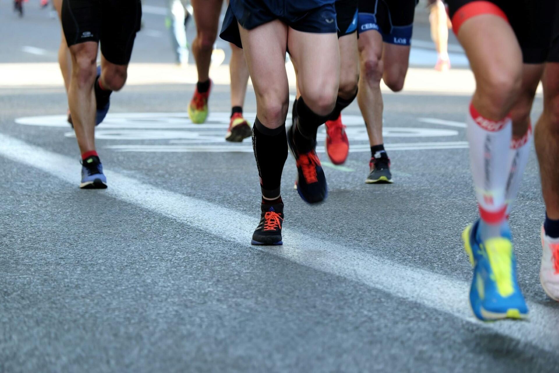 Runners’ legs and colorful running shoes during a road marathon race
