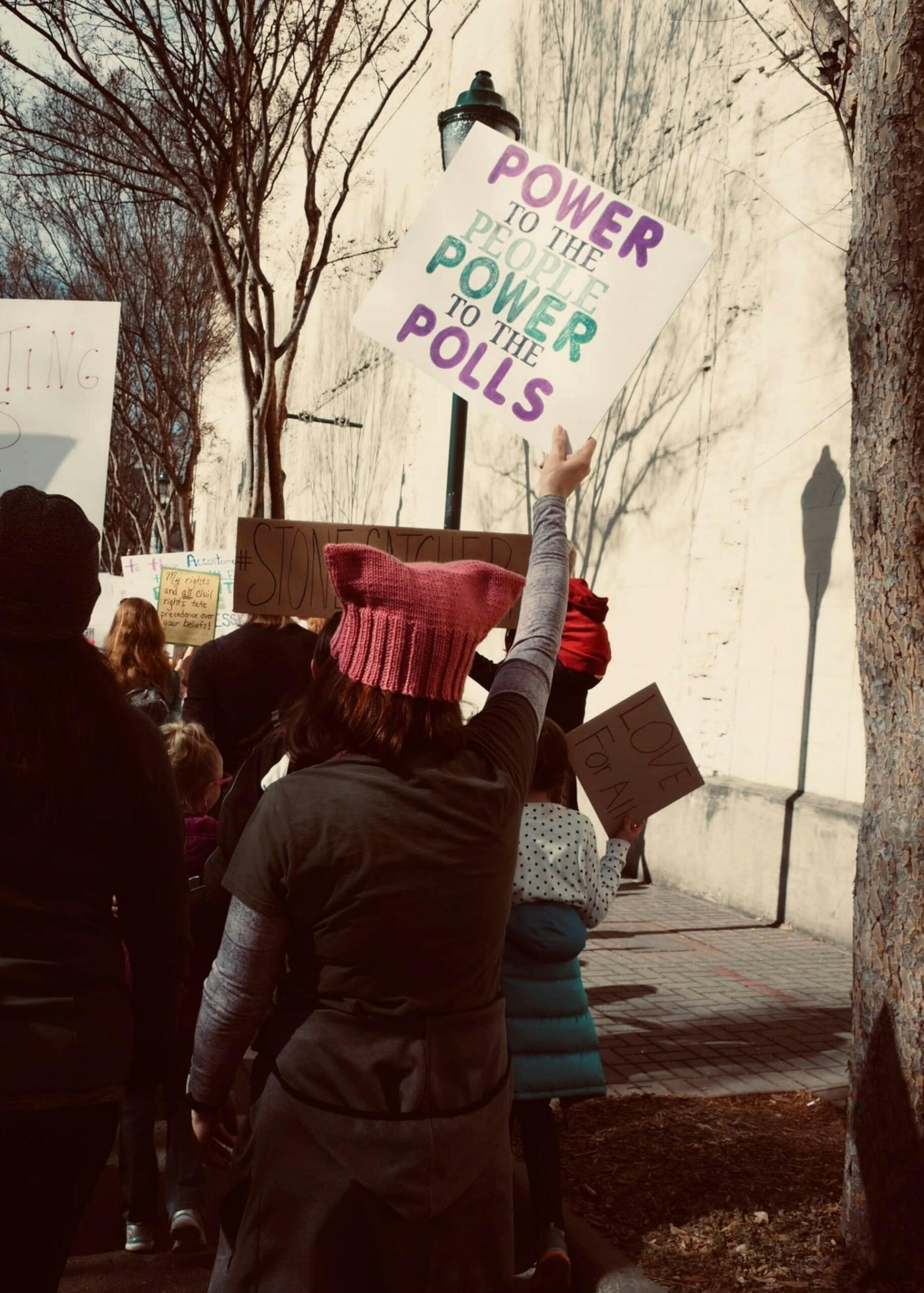 A protestor holding up a political sign written in green and purple ink. 