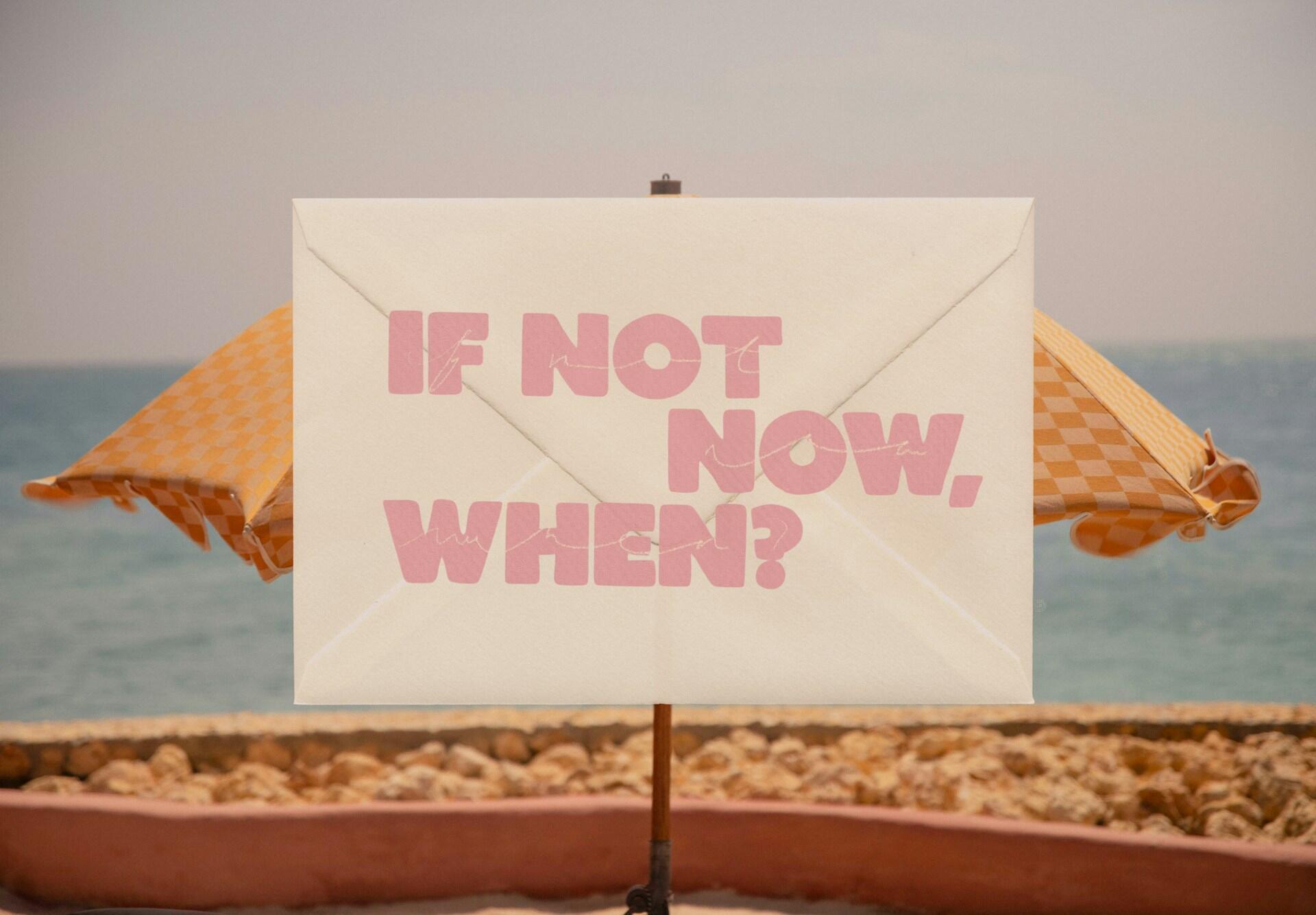 A yellow beach umbrella behind a sign with pink lettering on it.