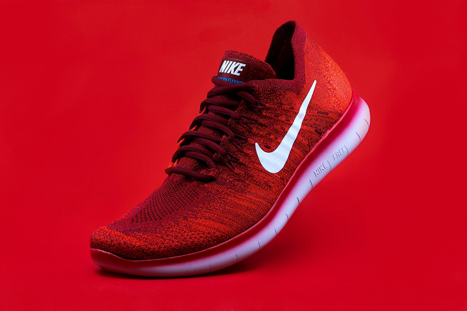 Red Nike running shoe on a red background.