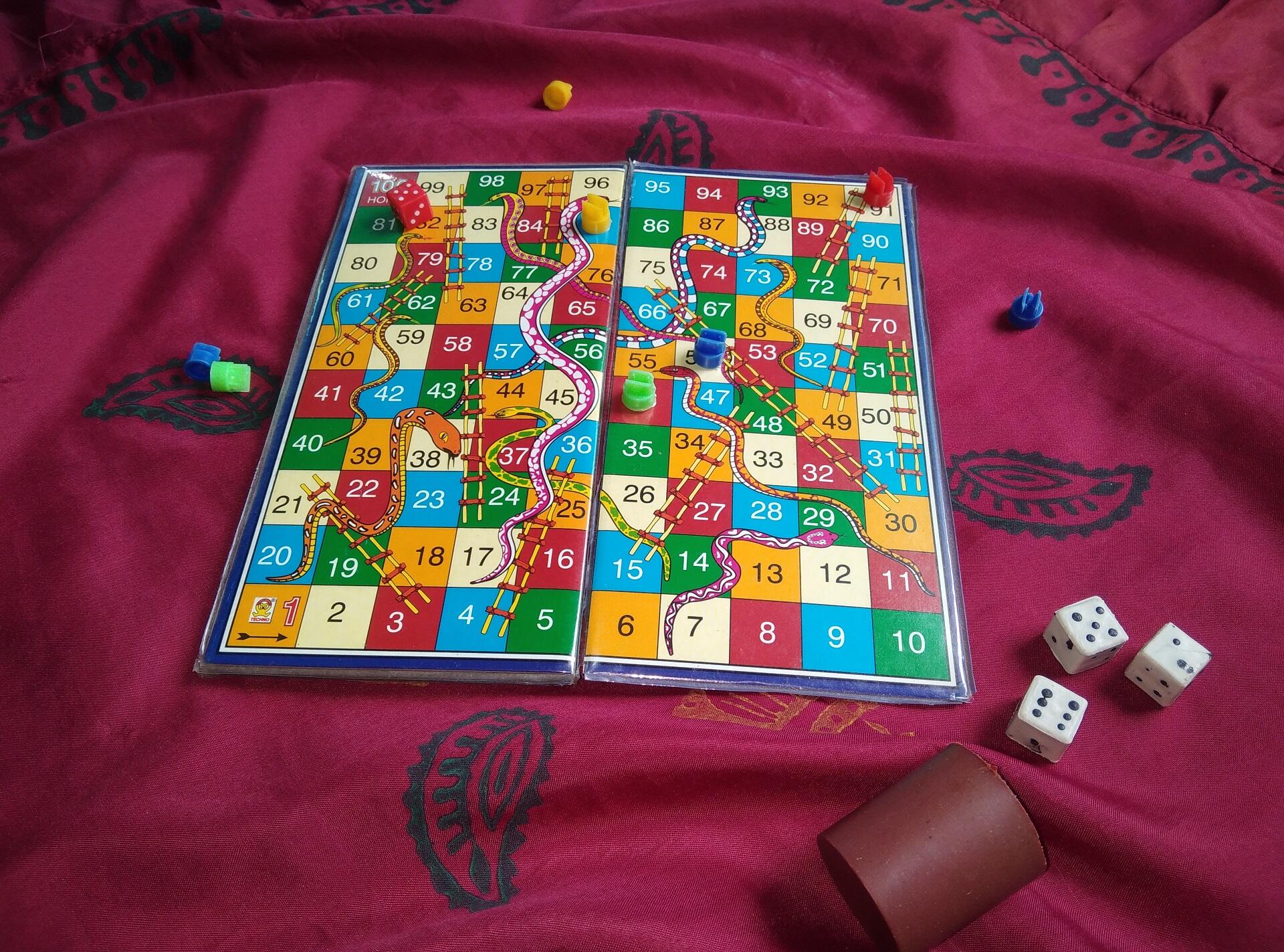 A board game with dice and tokens laying on a red cloth with a black pattern.