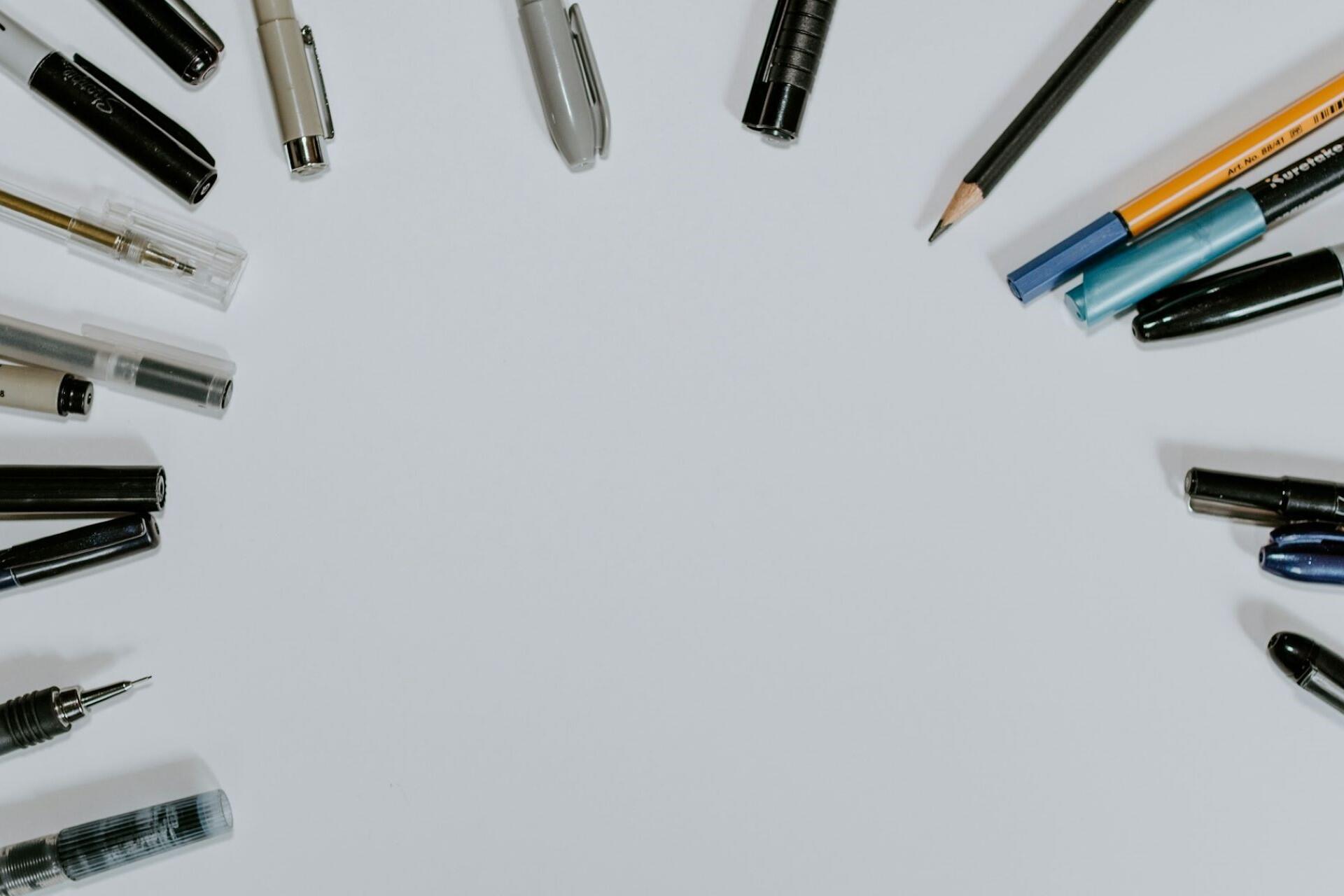 pens and pencils arranged around a blank desk workspace