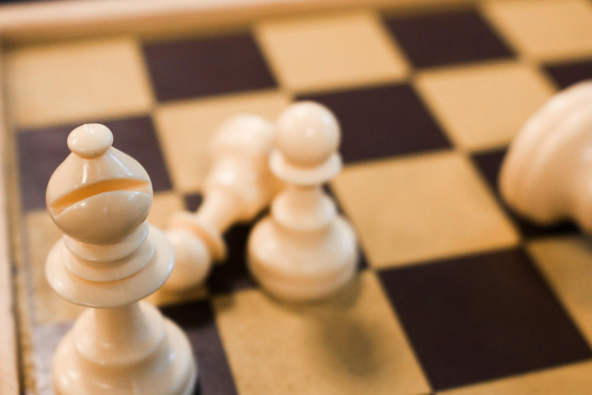 Close-up view of a white bishop and pawns positioned on a chessboard.