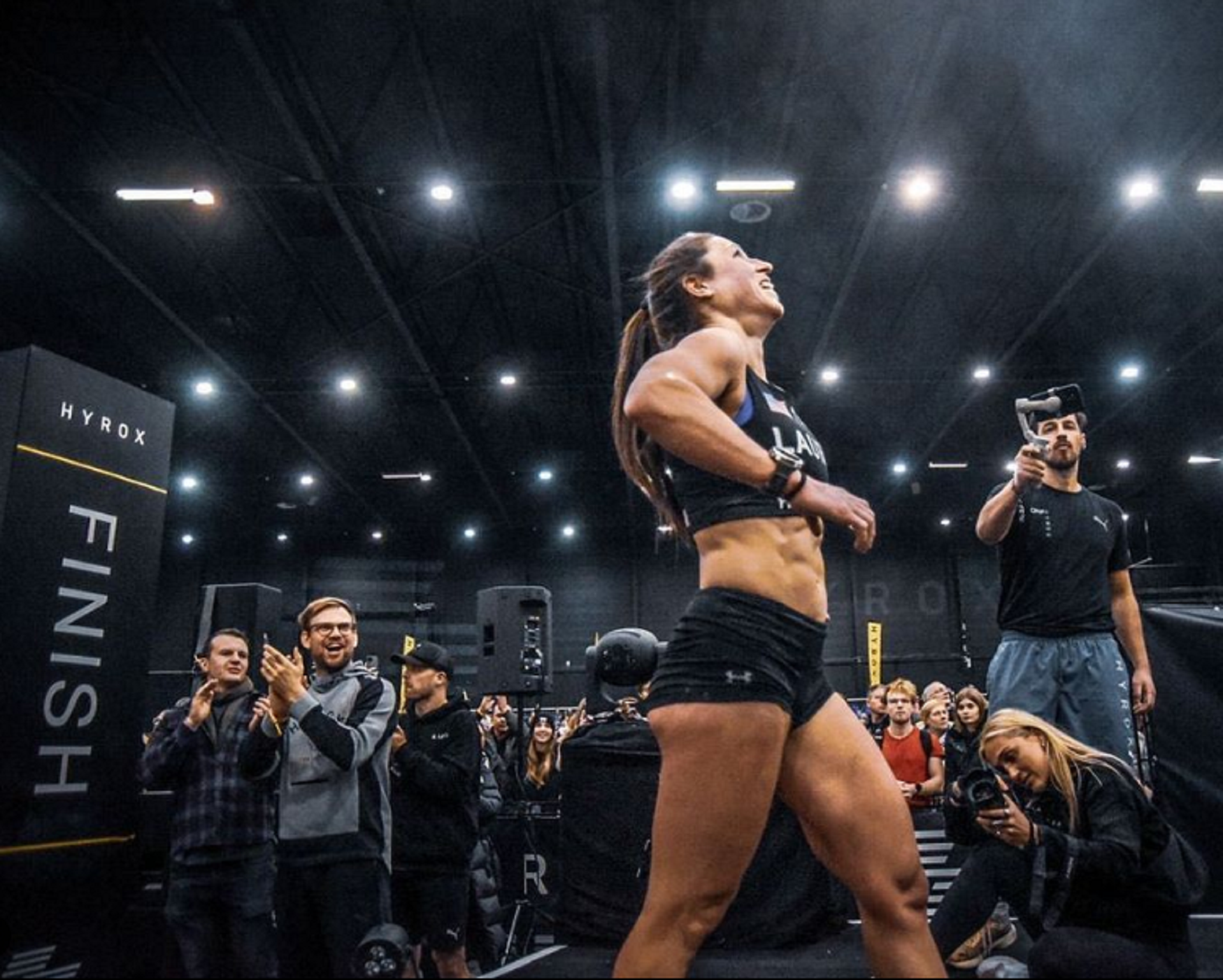 A person wering fitness clothing runs in front of enthusiastic spectators.