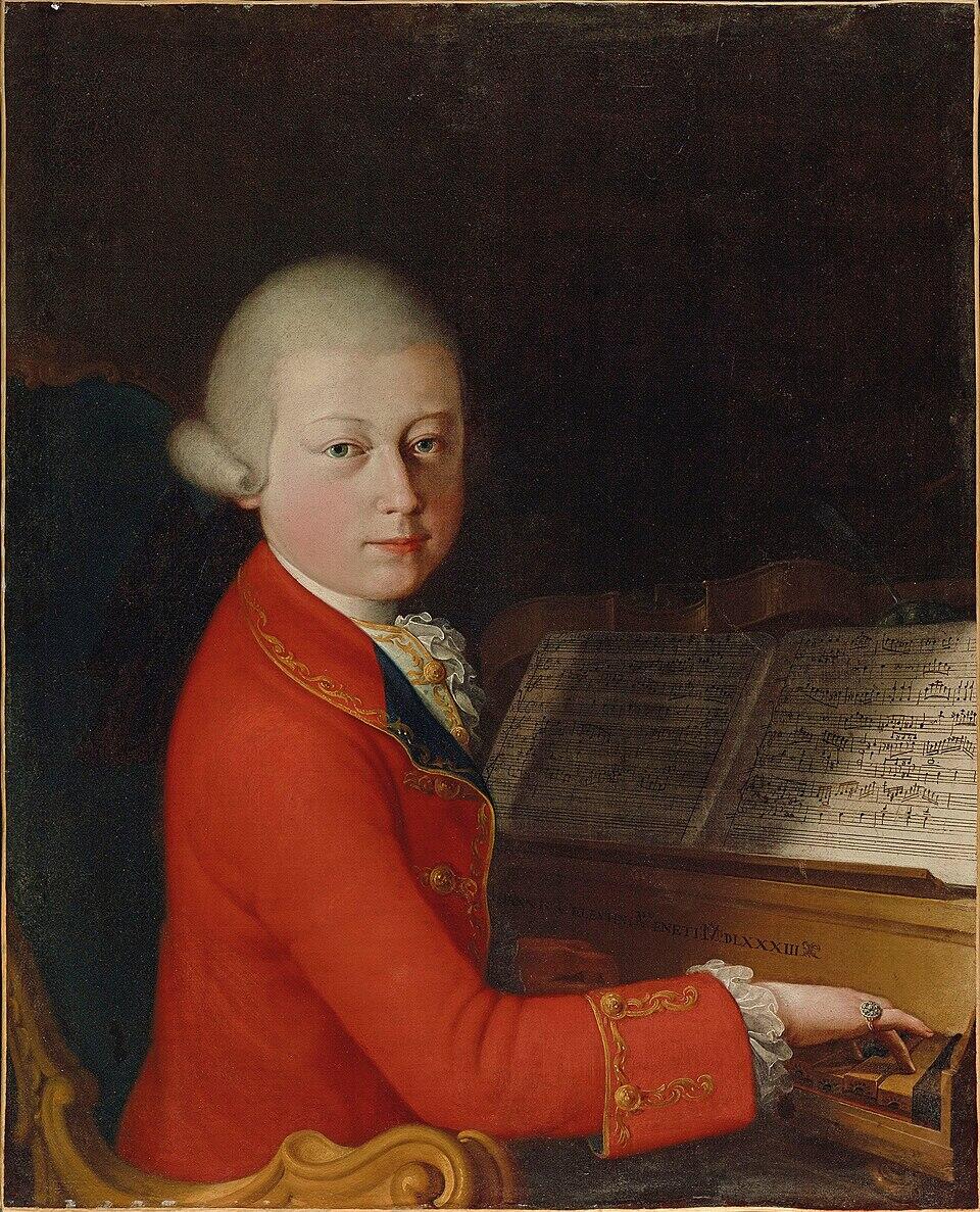 Portrait painting of a young Wolfgang Amadeus Mozart in a red coat seated at a keyboard instrument with sheet music.