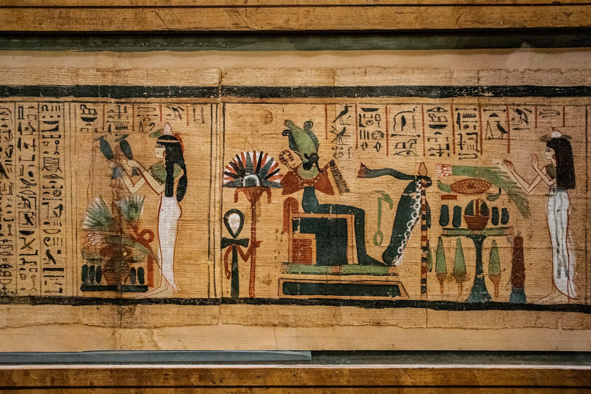 Ancient Egyptian papyrus with painted figures and columns of hieroglyphic writing.