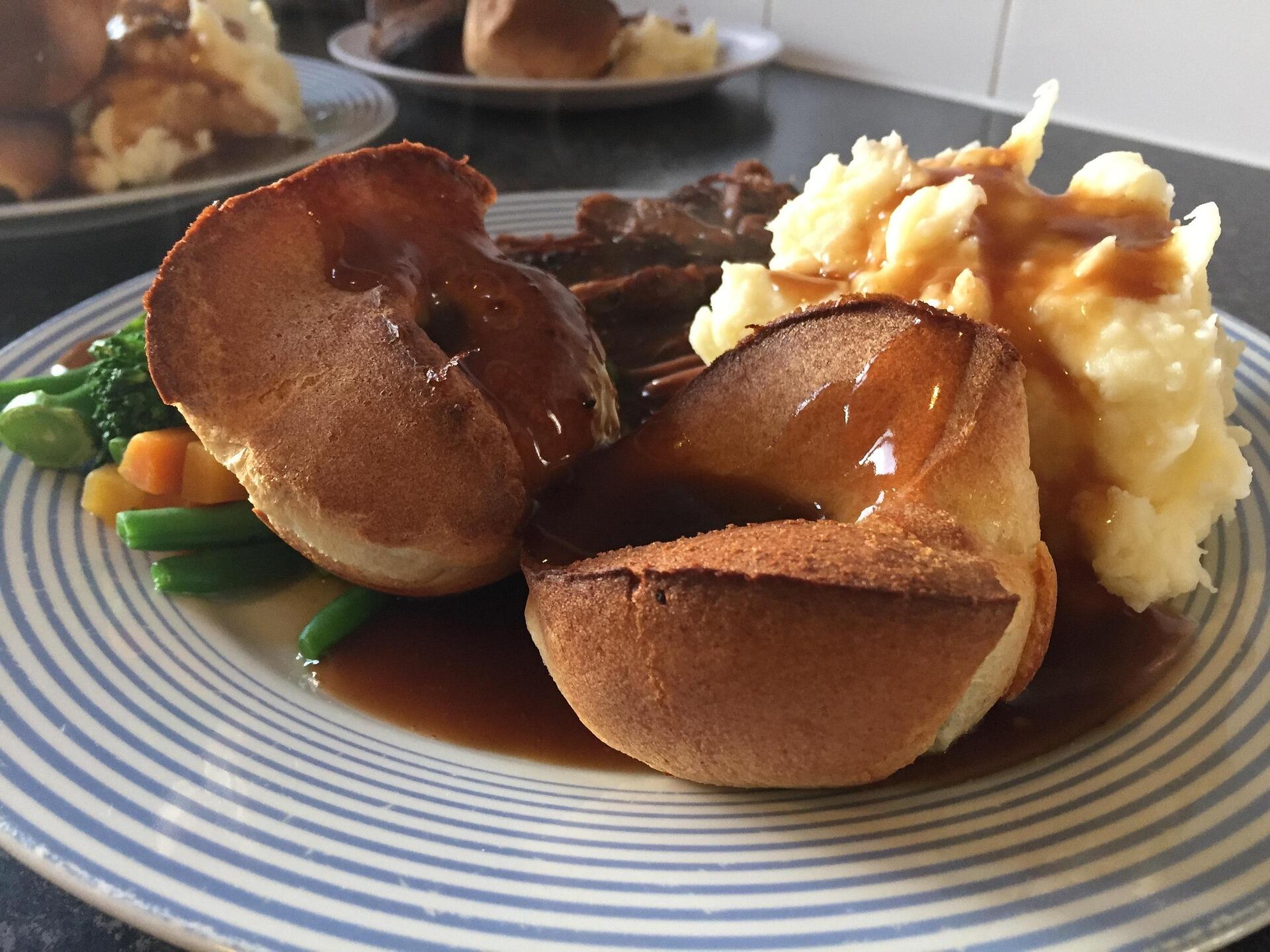 Image of a roast dinner, Yorkshire puddings, mash and gravy on a plate