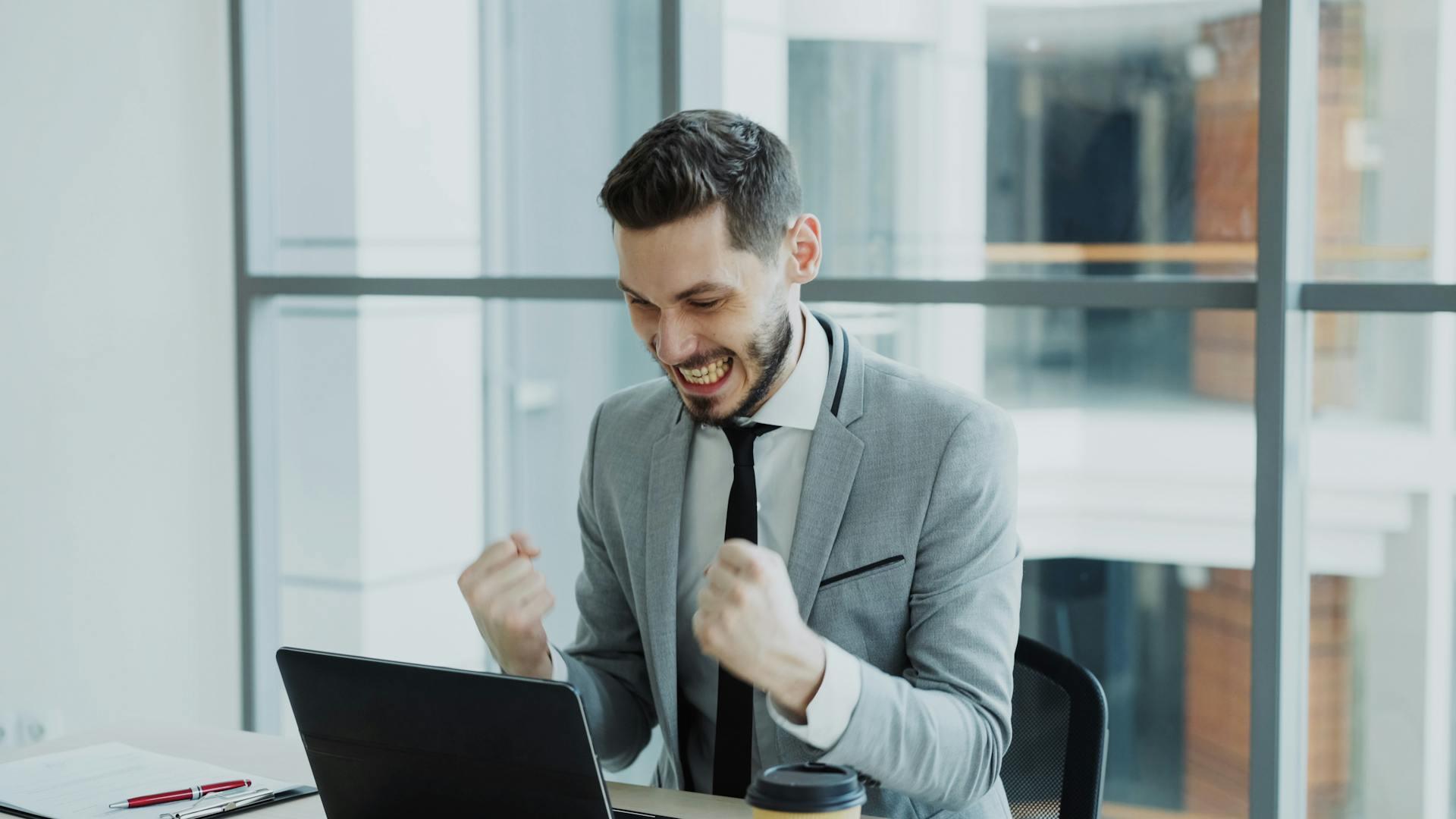 Man in suit looking elated while looking at his laptop