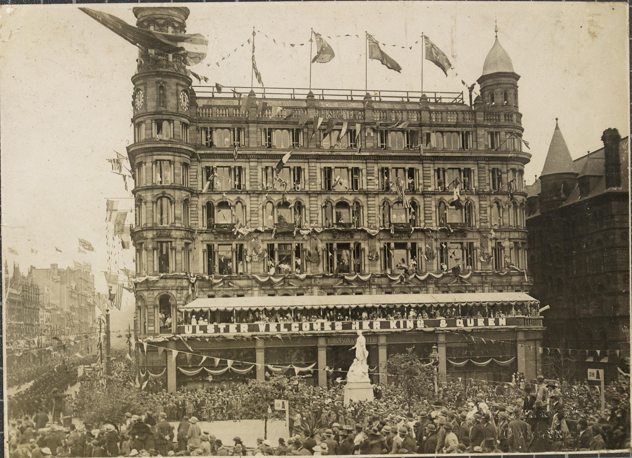 Large store covered in flags with crowds of people outside, sepia toned 