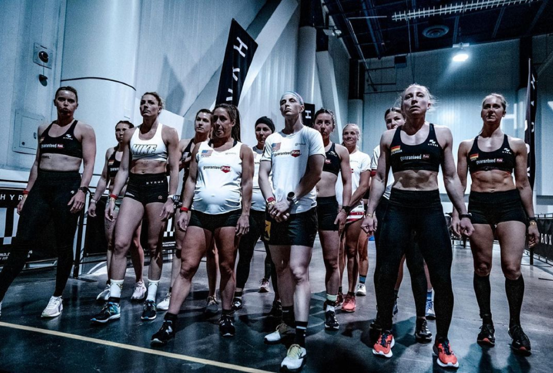 A group of female athletes in sports clothing gather at a race's starting line.