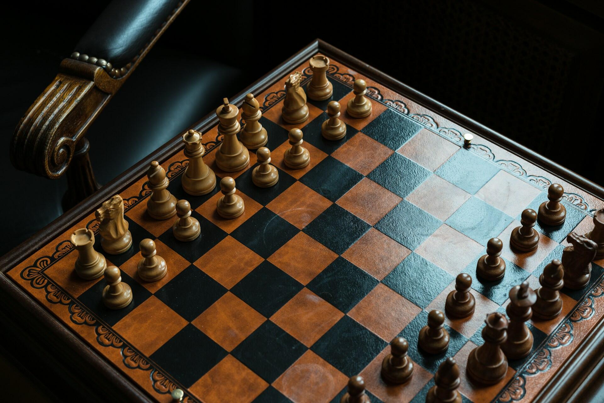 Wooden chessboard with pieces set up for a game viewed from above