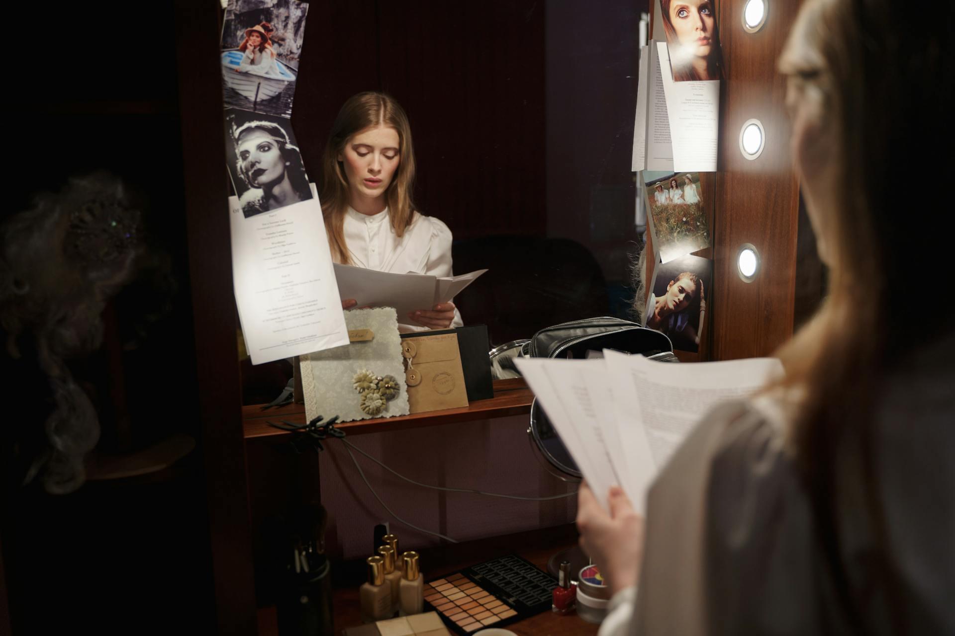 an actress reading a script while looking in a mirror