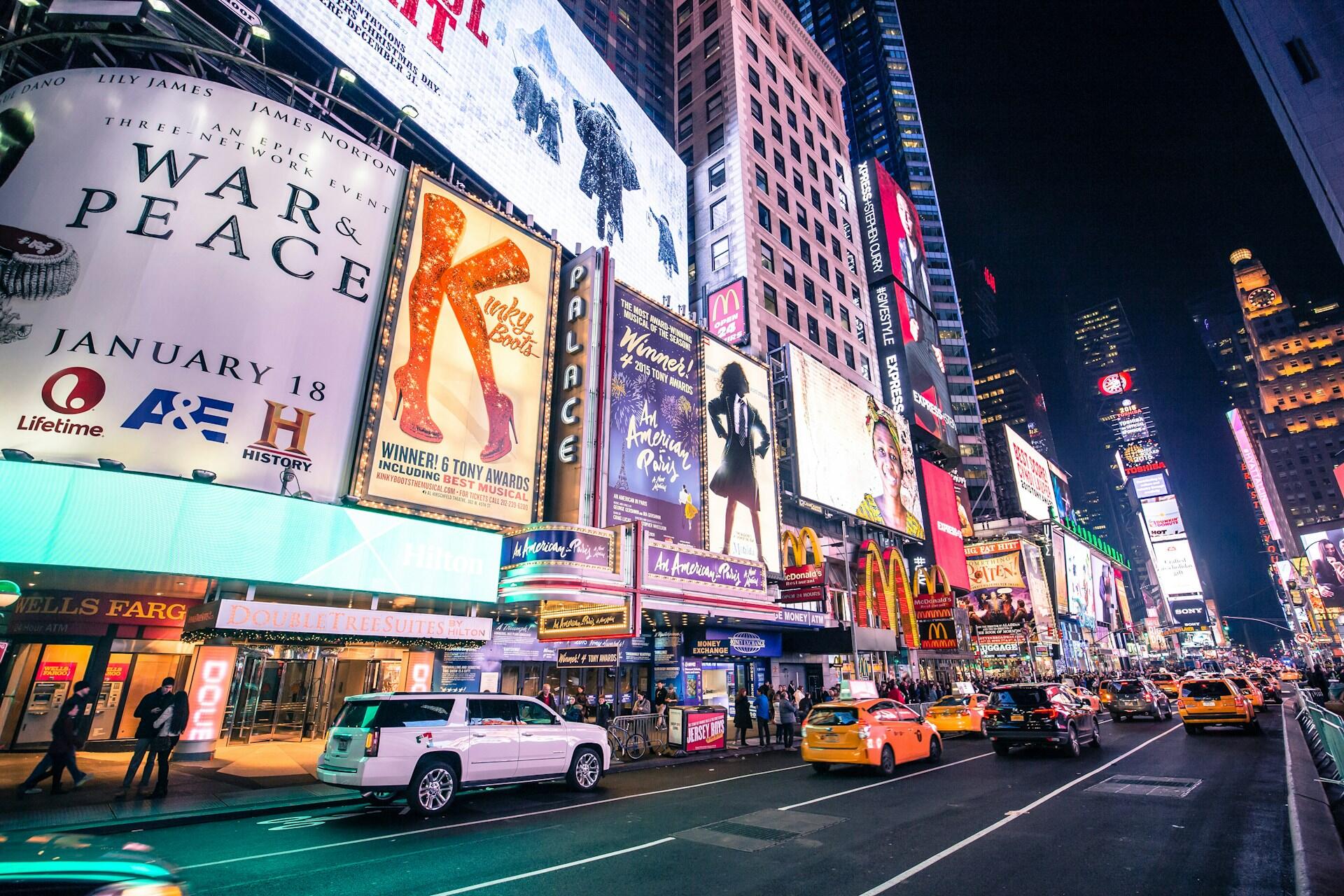 Busy street in Times Square with many ads for different Broadway shows posted