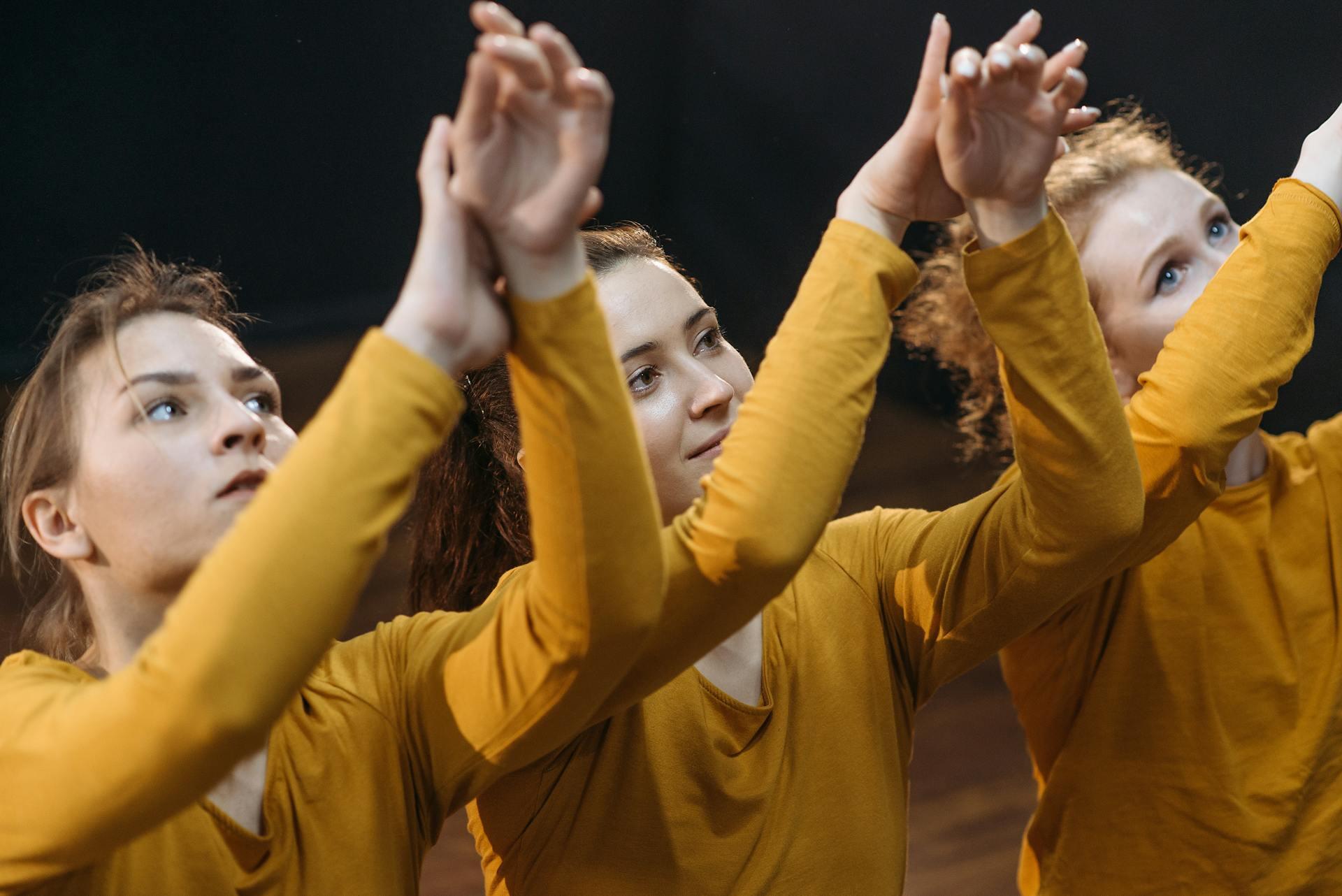 actresses dancing together on stage all wearing yellow shirts