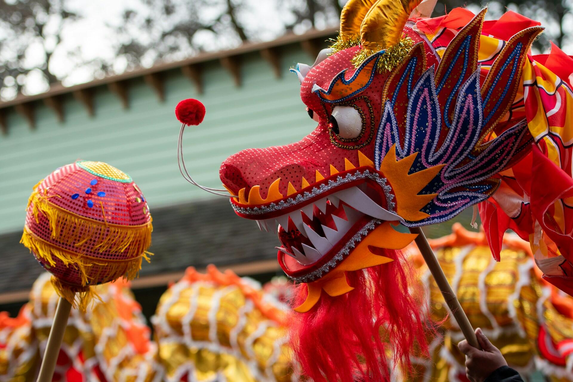 A paper mache dragon head facing an array of Chinese lanterns.