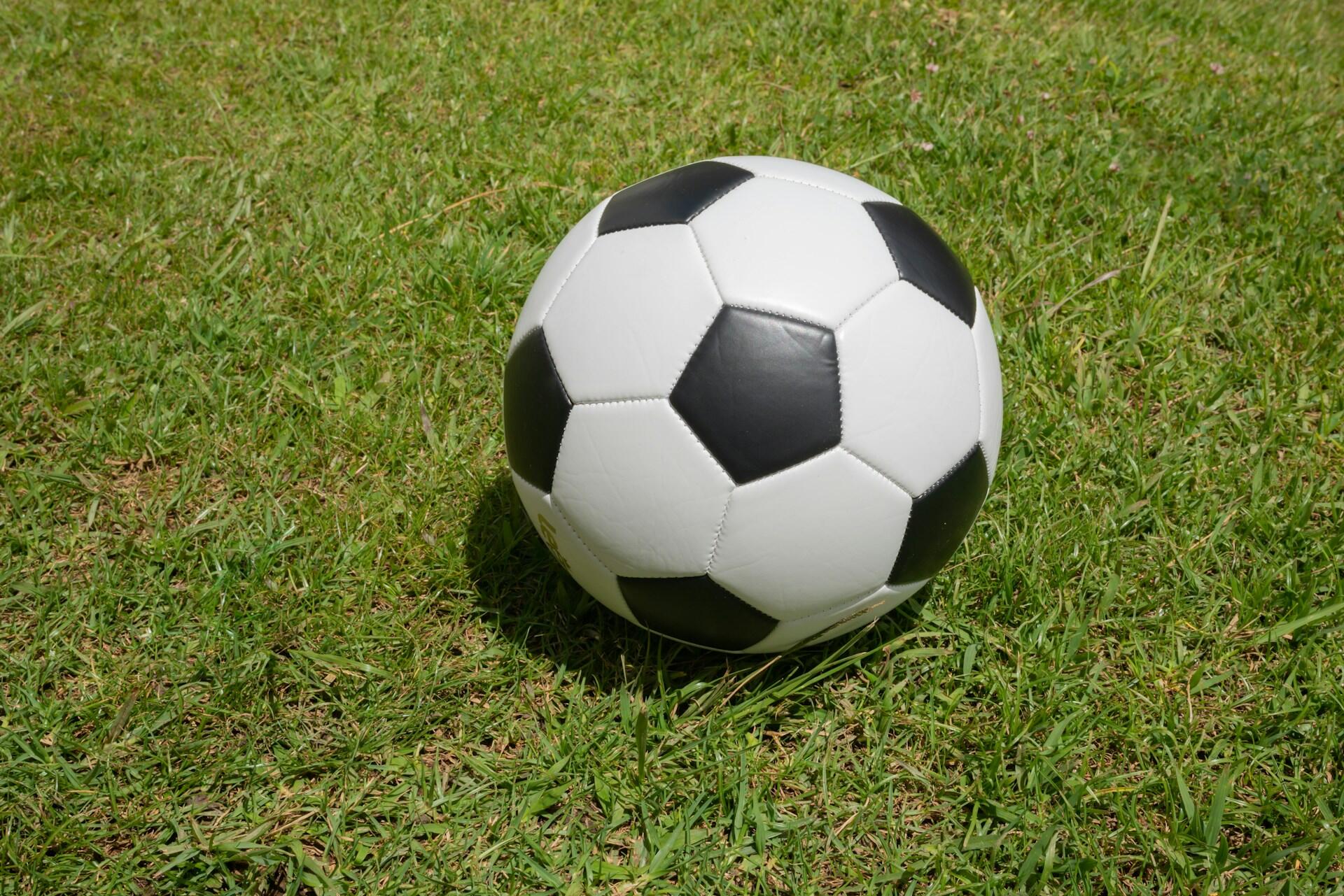 Black-and-white football on a grass pitch.