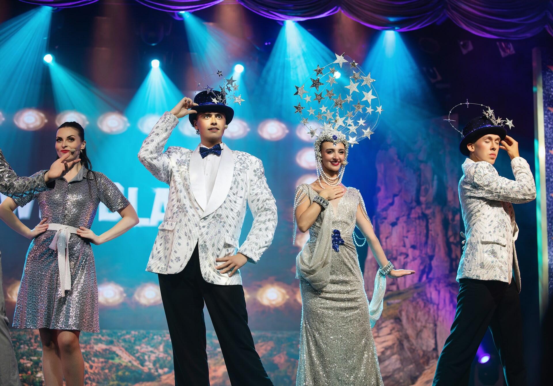Actors on stage wearing flashy costumes