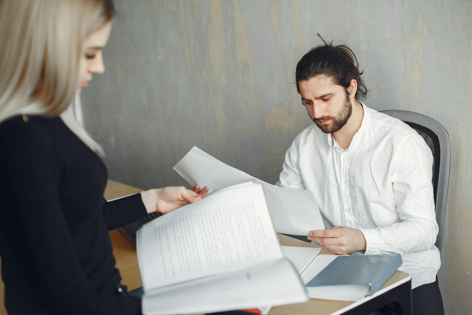 Two individuals reviewing documents together at a desk in a professional setting.