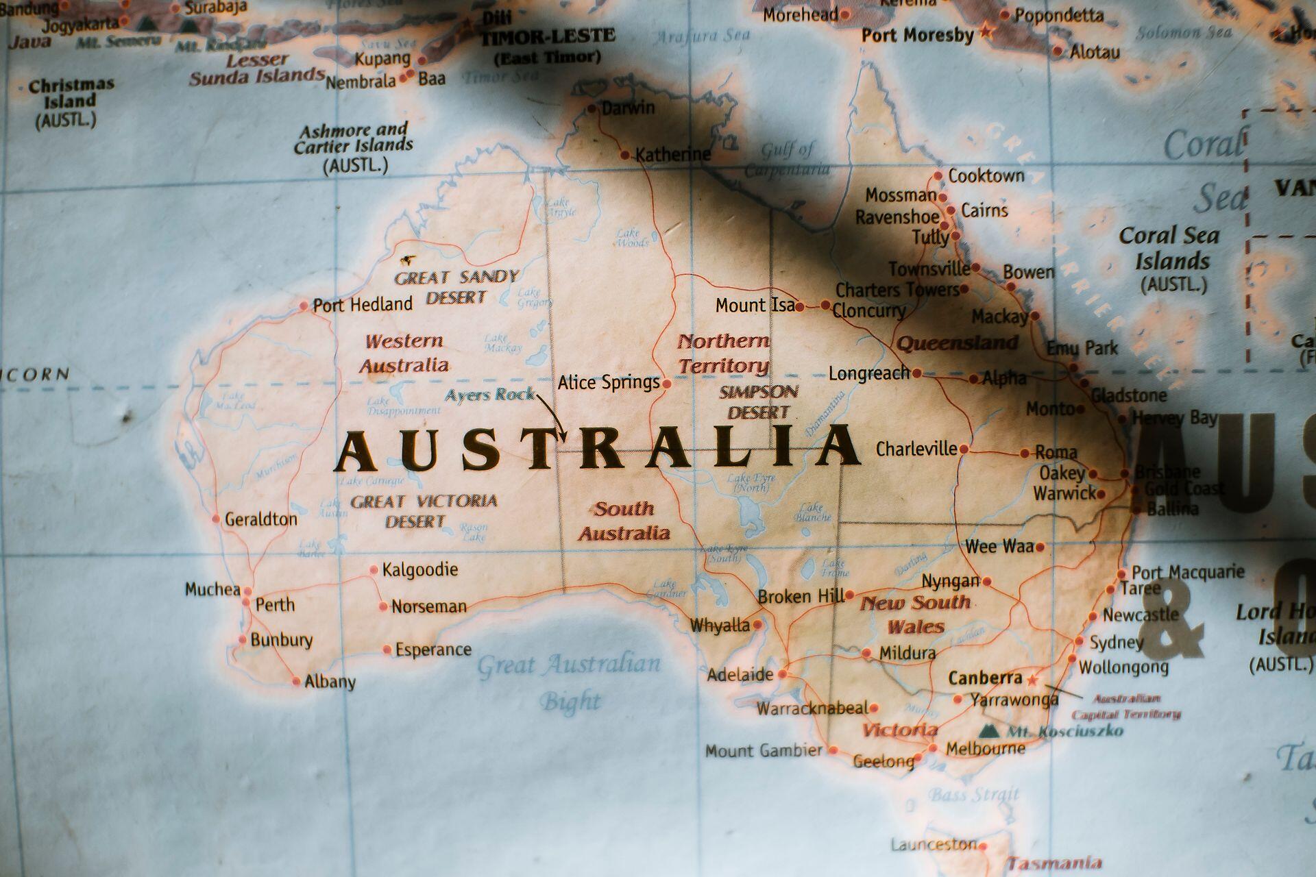 Map of Australia showing states, major cities, deserts, and surrounding seas with a shadow partially covering the eastern region.