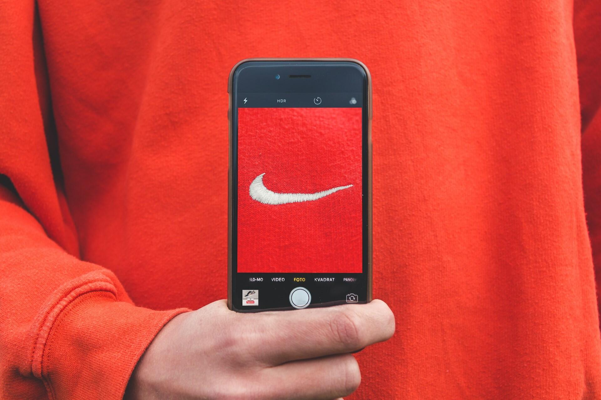 Person photographing a recognisable logo on a red hoodie
