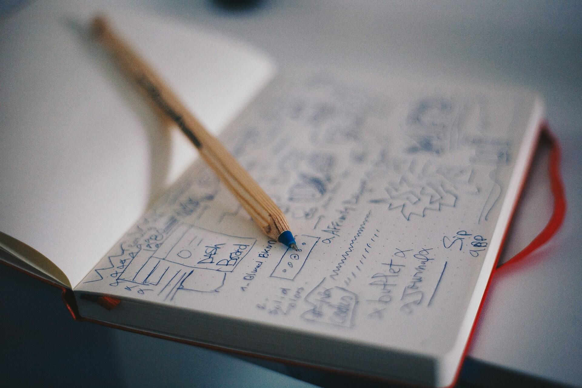 Pencil on a sketchbook with rough logo ideas and brand design notes