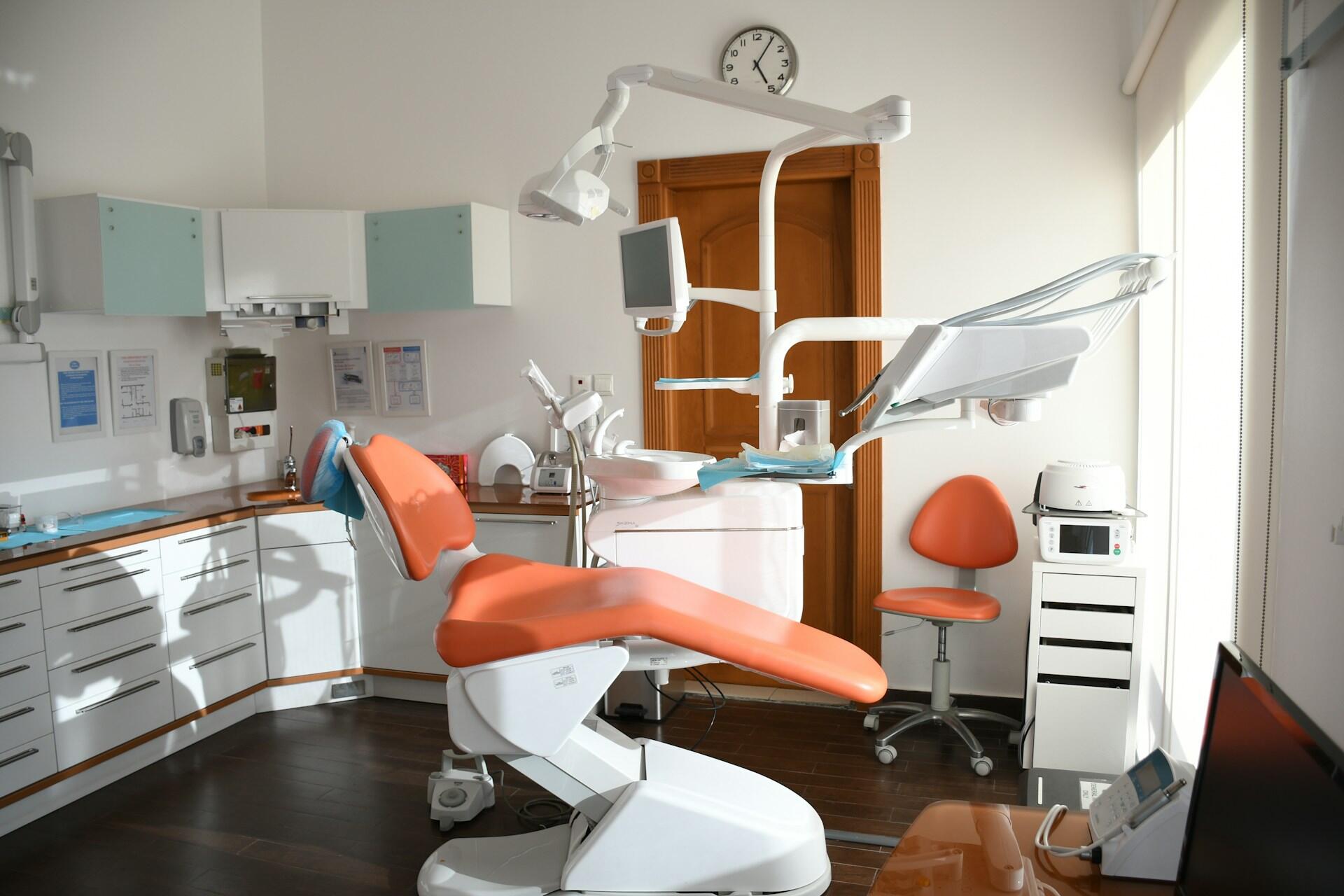Empty dental clinic with an orange dental chair and dental equipment