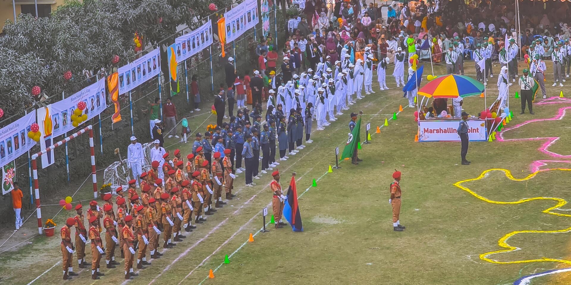An array of men in formal military uniform surround a sports pitch with officials and athletes on it.
