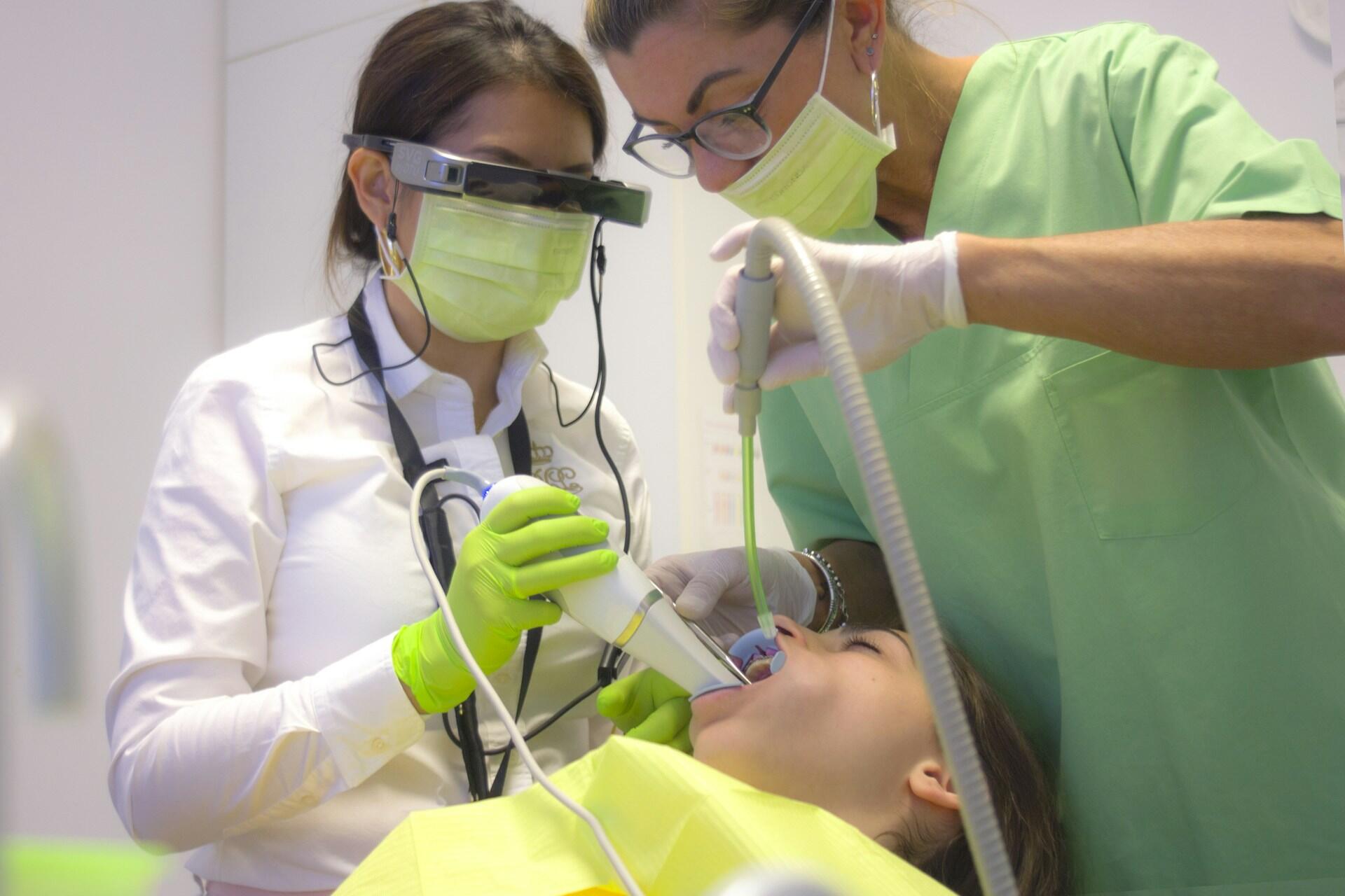Two dental professionals treating a patient in a dental chair