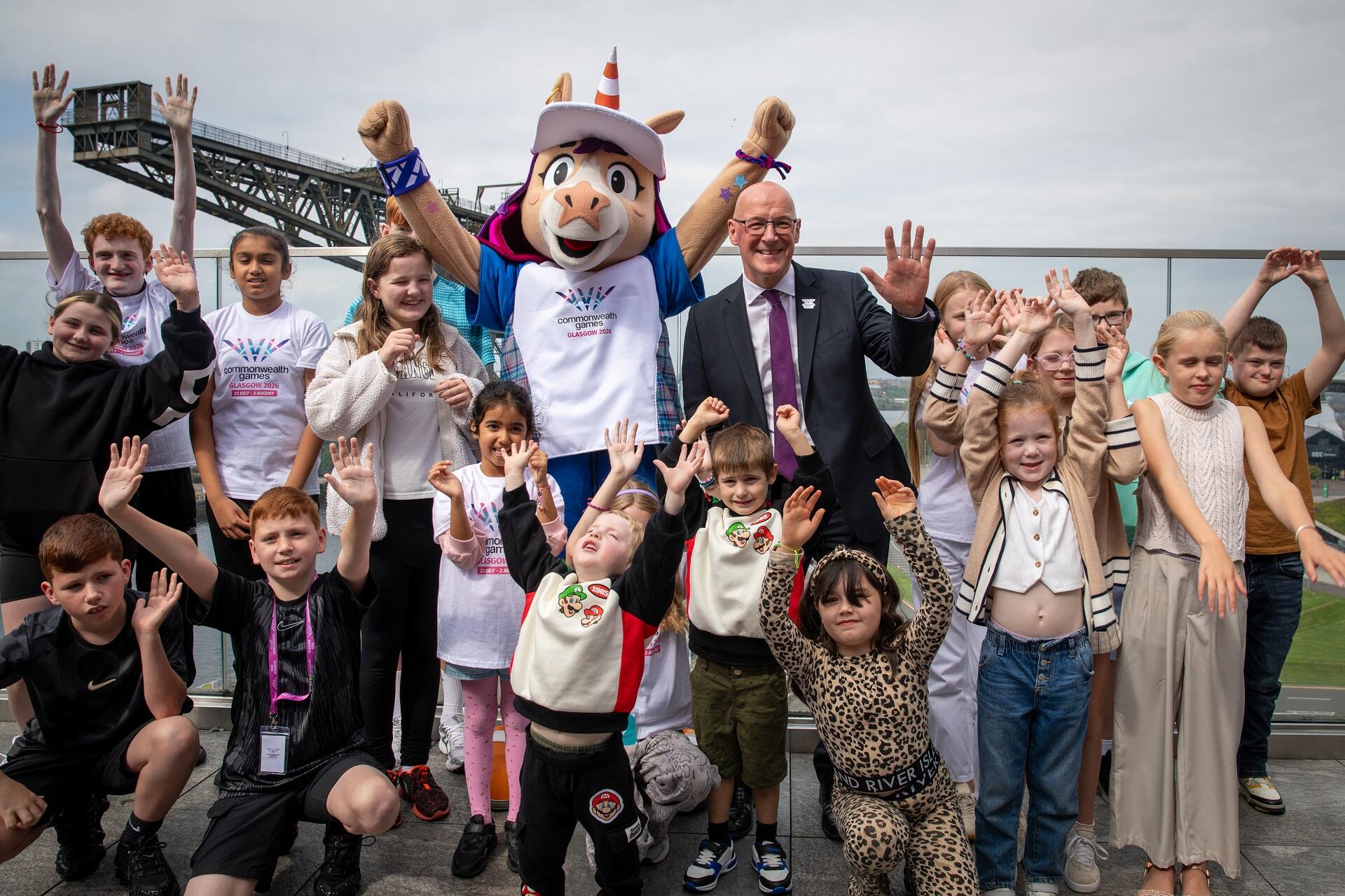 A person dressed as a cartoon unicorn surrounded by children and a man in a suit.
