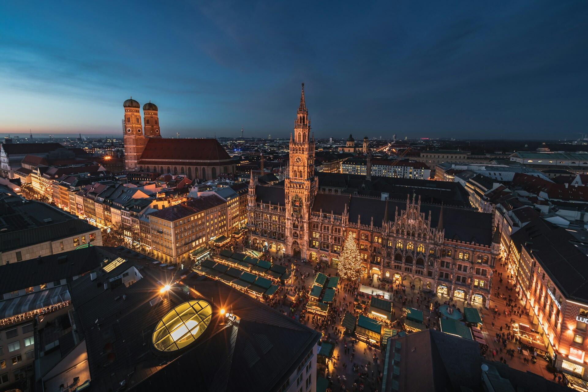 An aerial view of Munich at night with illuminated buildings and a large square