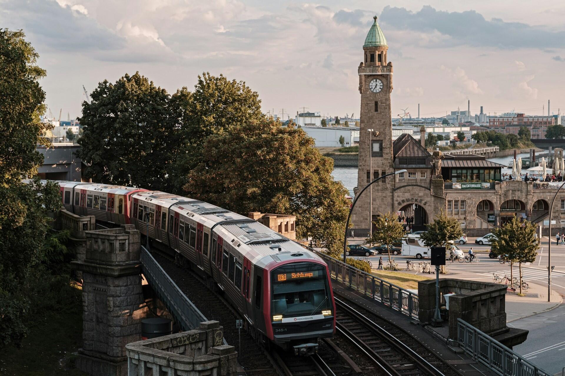 A train passing near a clock tower and waterfront buildings