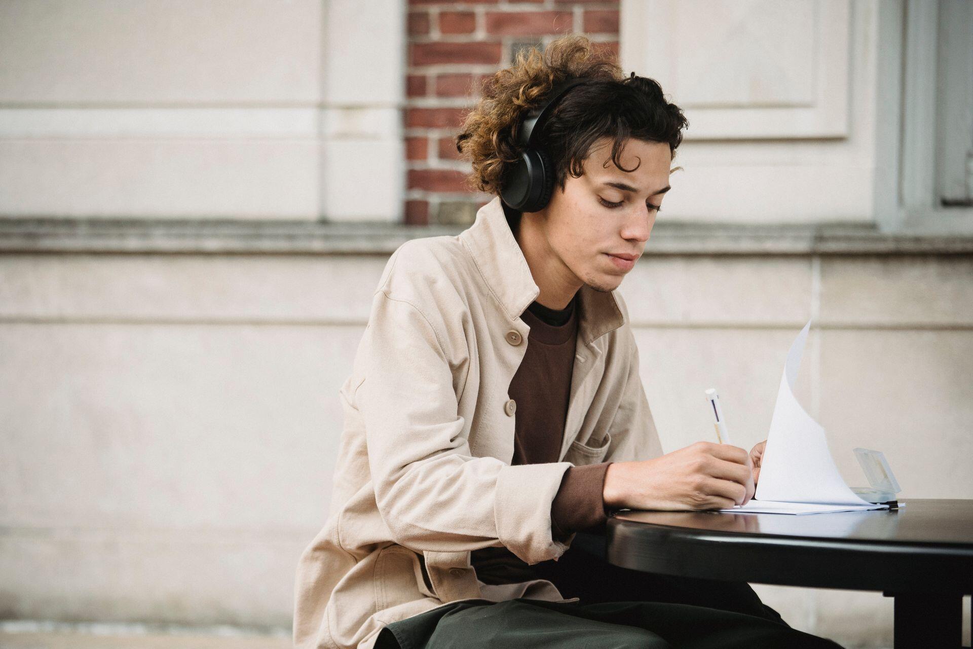 Man wearing headphones writing on paper