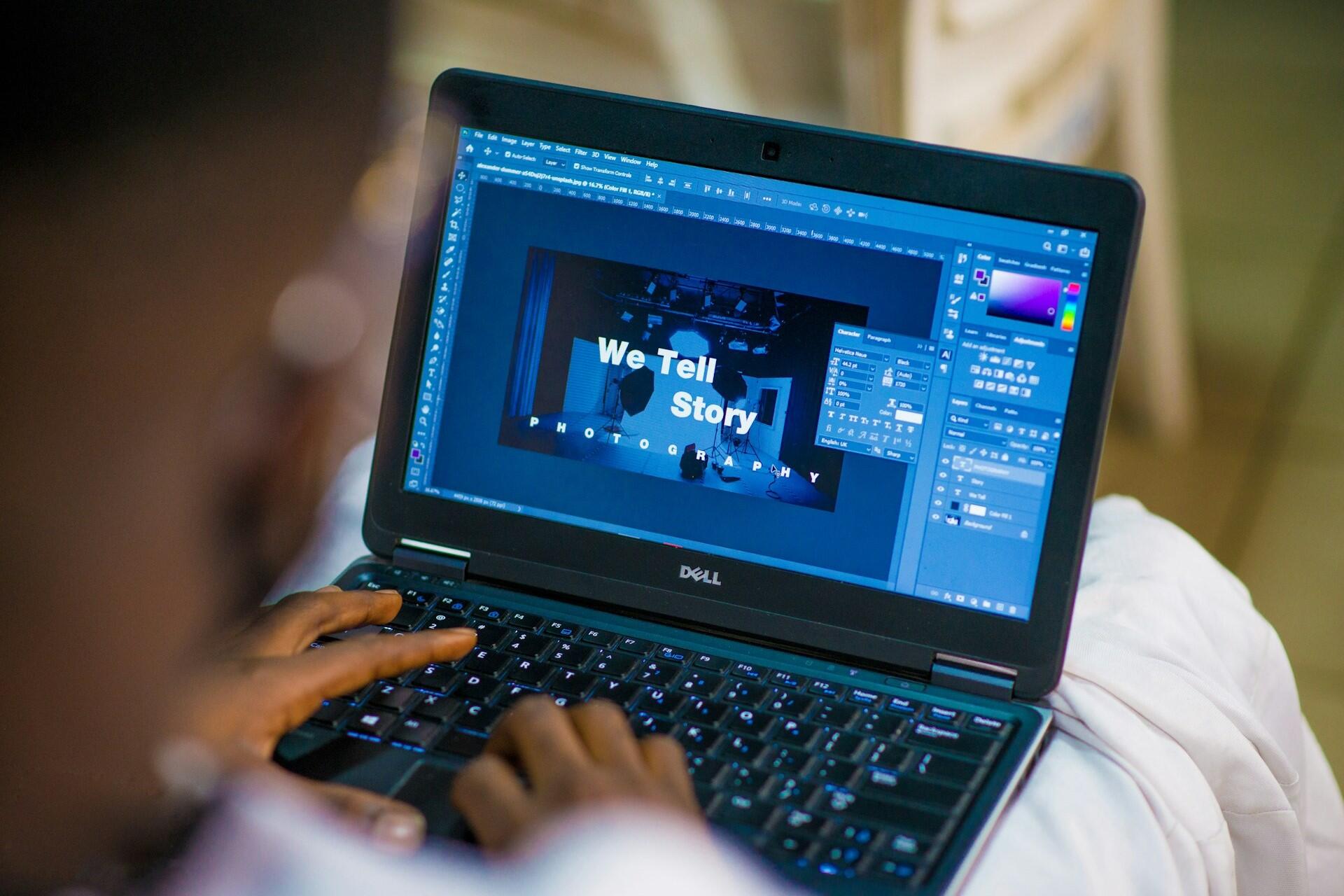 Designer working on text layout and visual editing software on a laptop