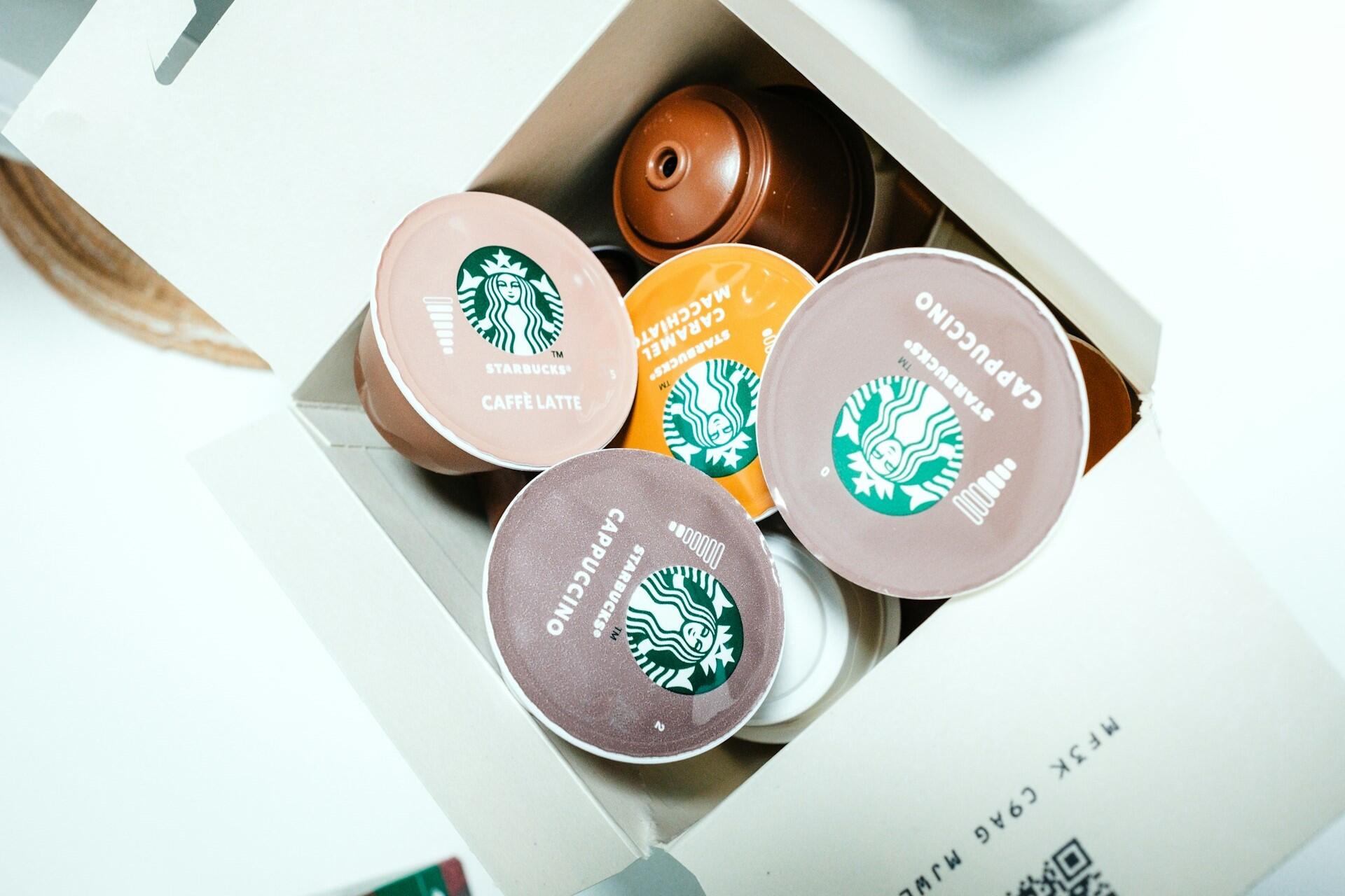 Coffee capsules inside a cardboard box with branded lids visible