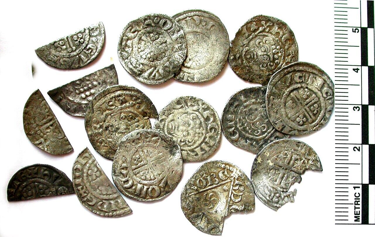 Medieval silver pennies next to a ruler