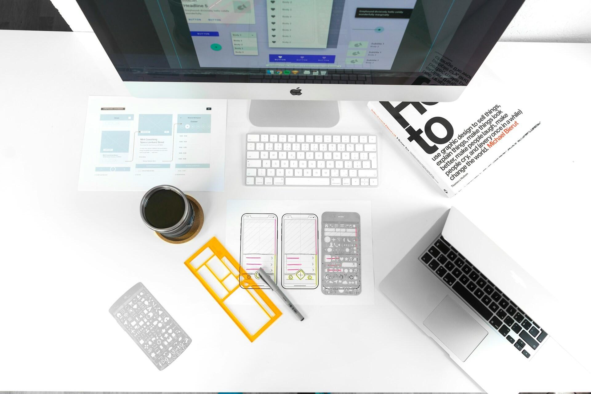UI design workspace with wireframes, laptop, keyboard, and design materials on a desk